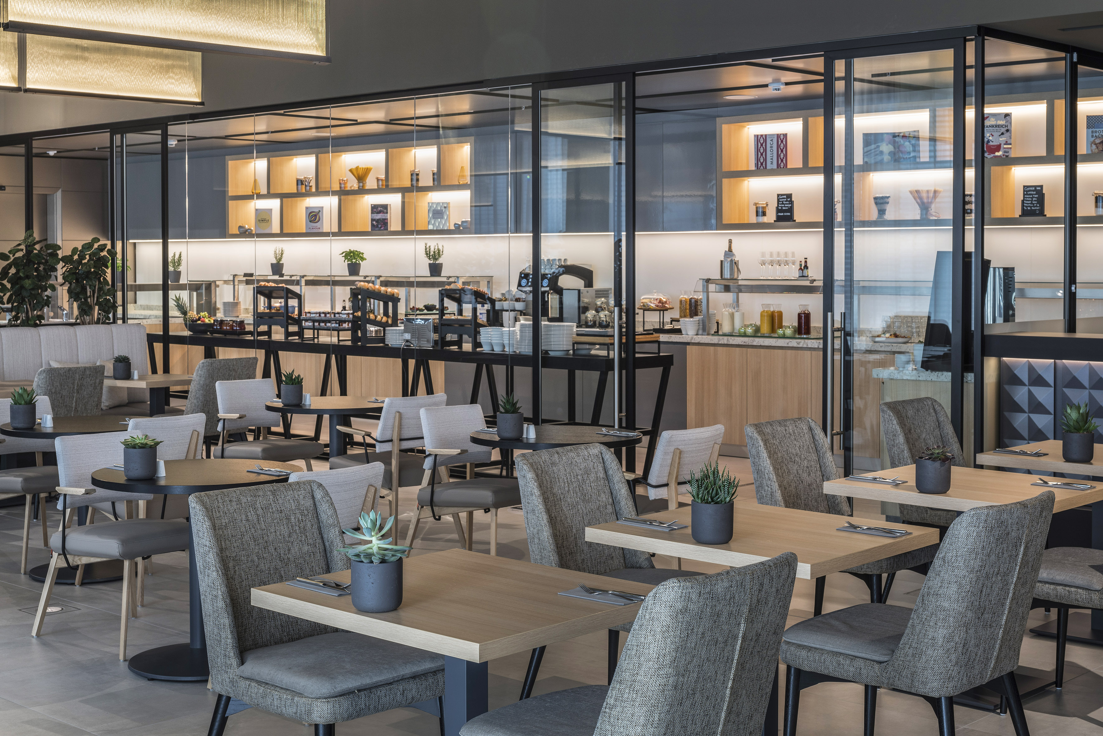 Modern restaurant interior featuring a breakfast buffet and dining tables.
