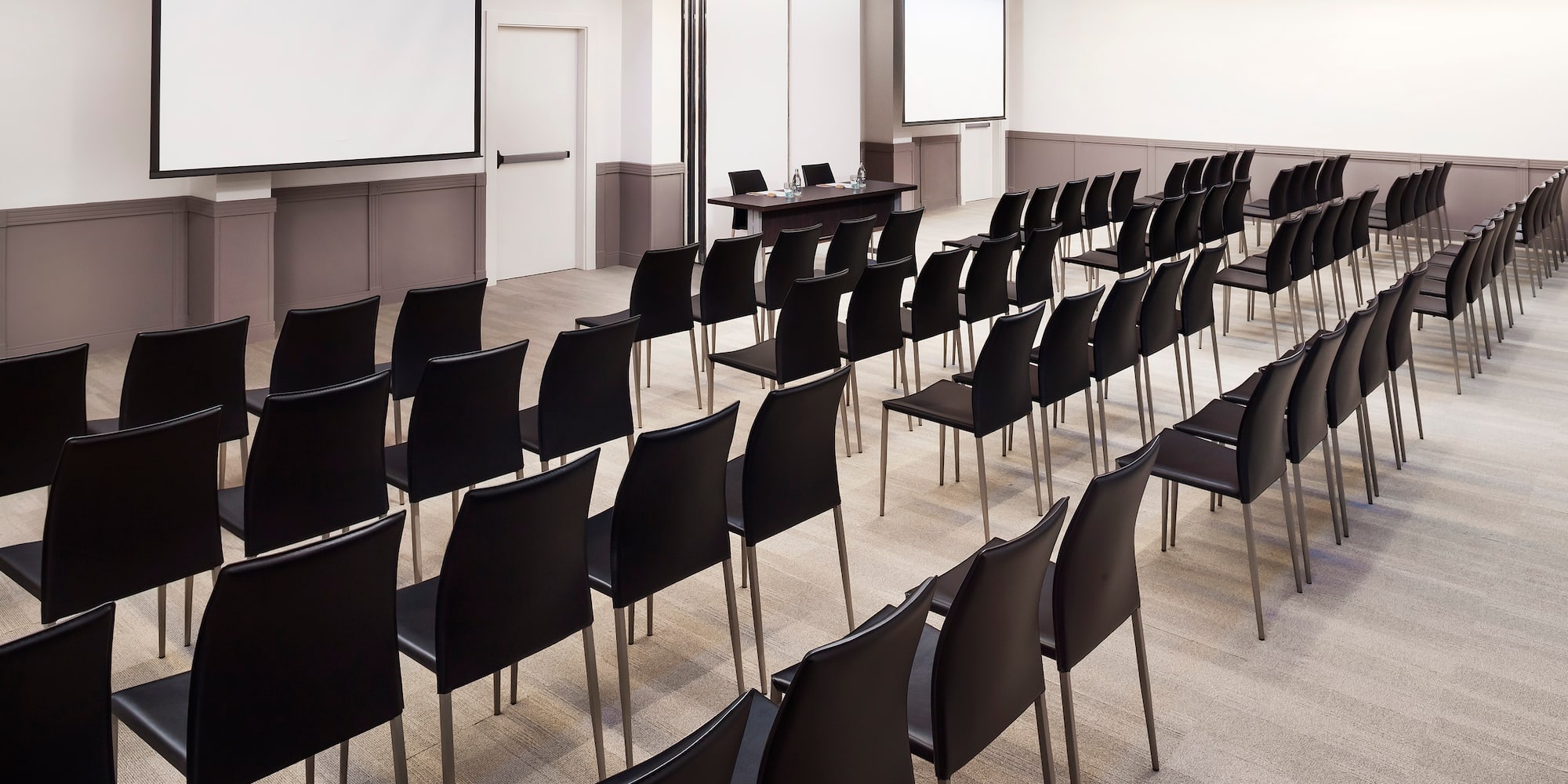 a room with black chairs and a projector screen