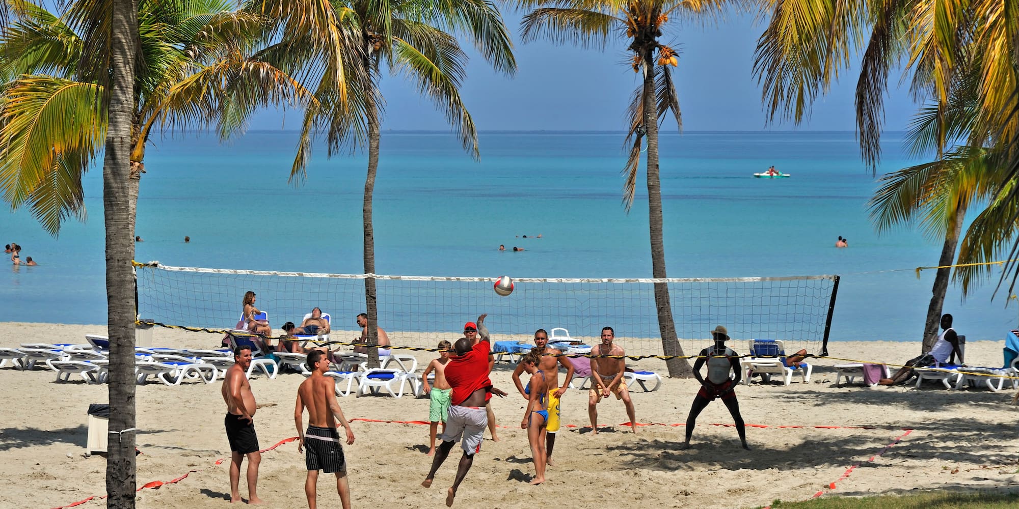 a group of people playing volleyball on a beach