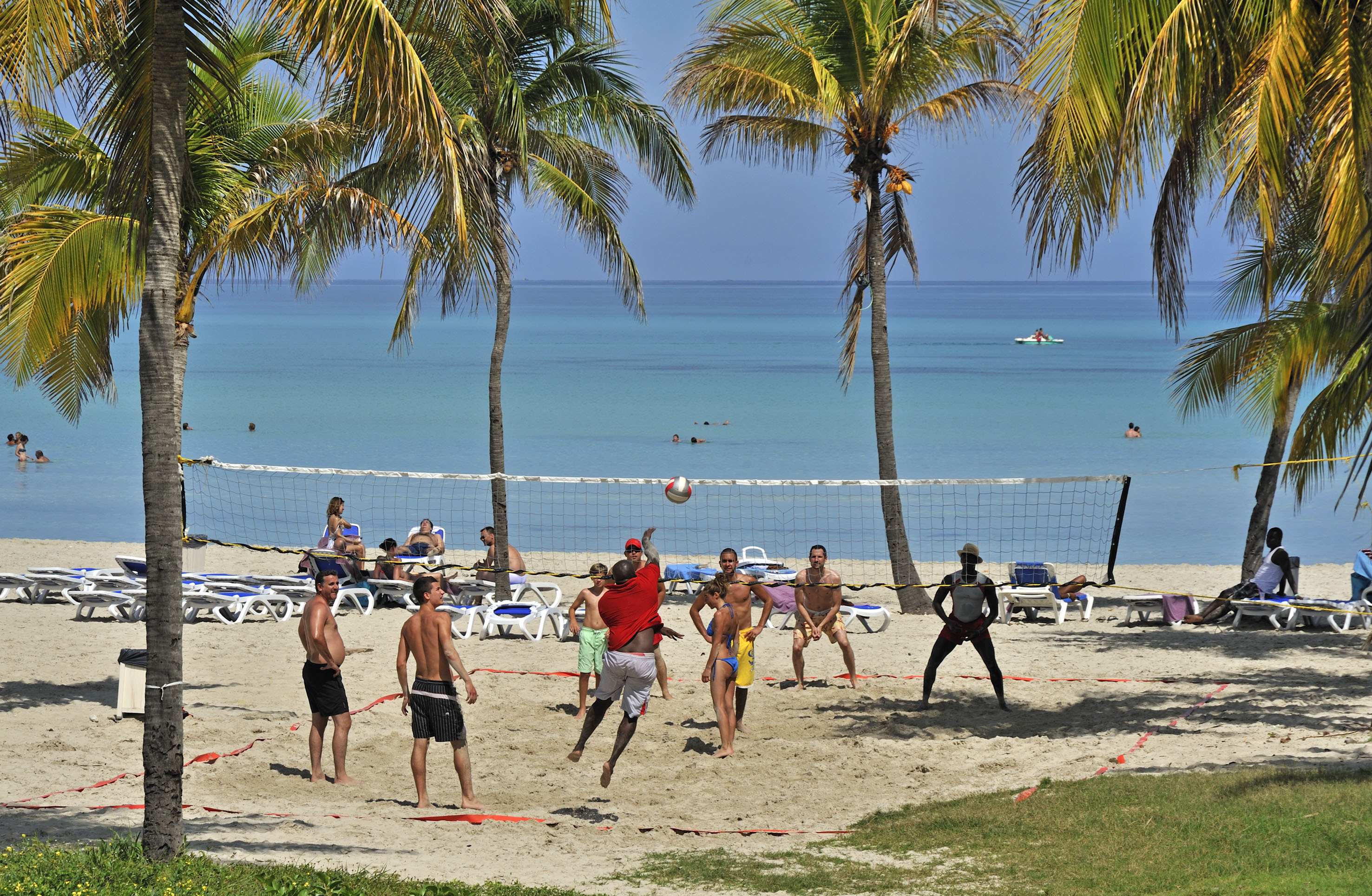 a group of people playing volleyball on a beach