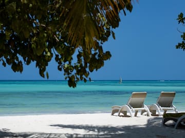 chairs on a beach with a sailboat in the background