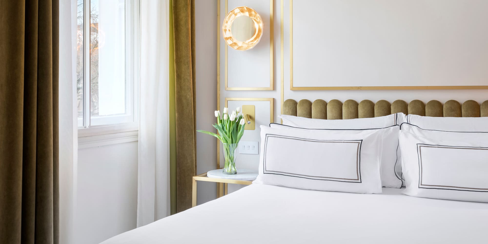 a bed with white sheets and pillows in a room with a window