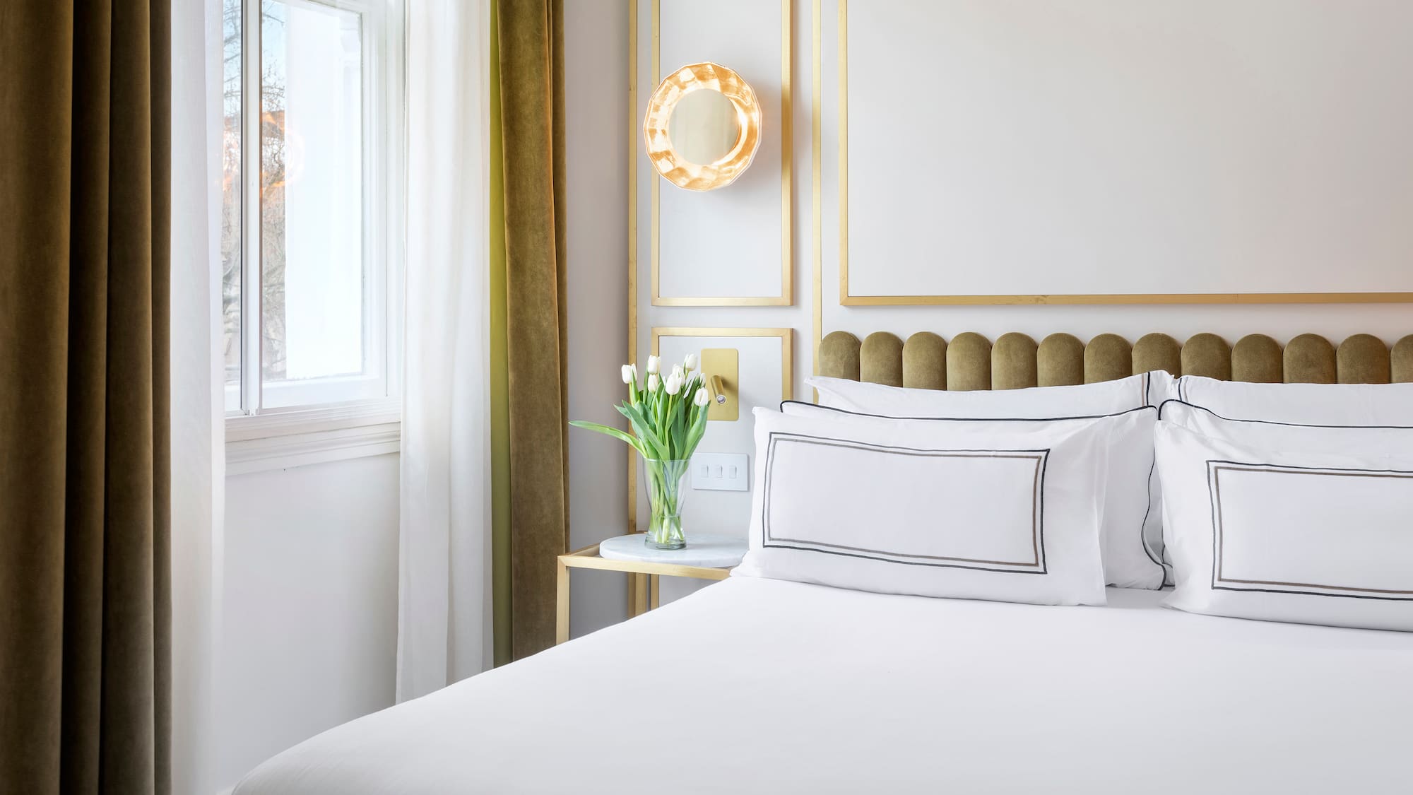 a bed with white sheets and pillows in a room with a window