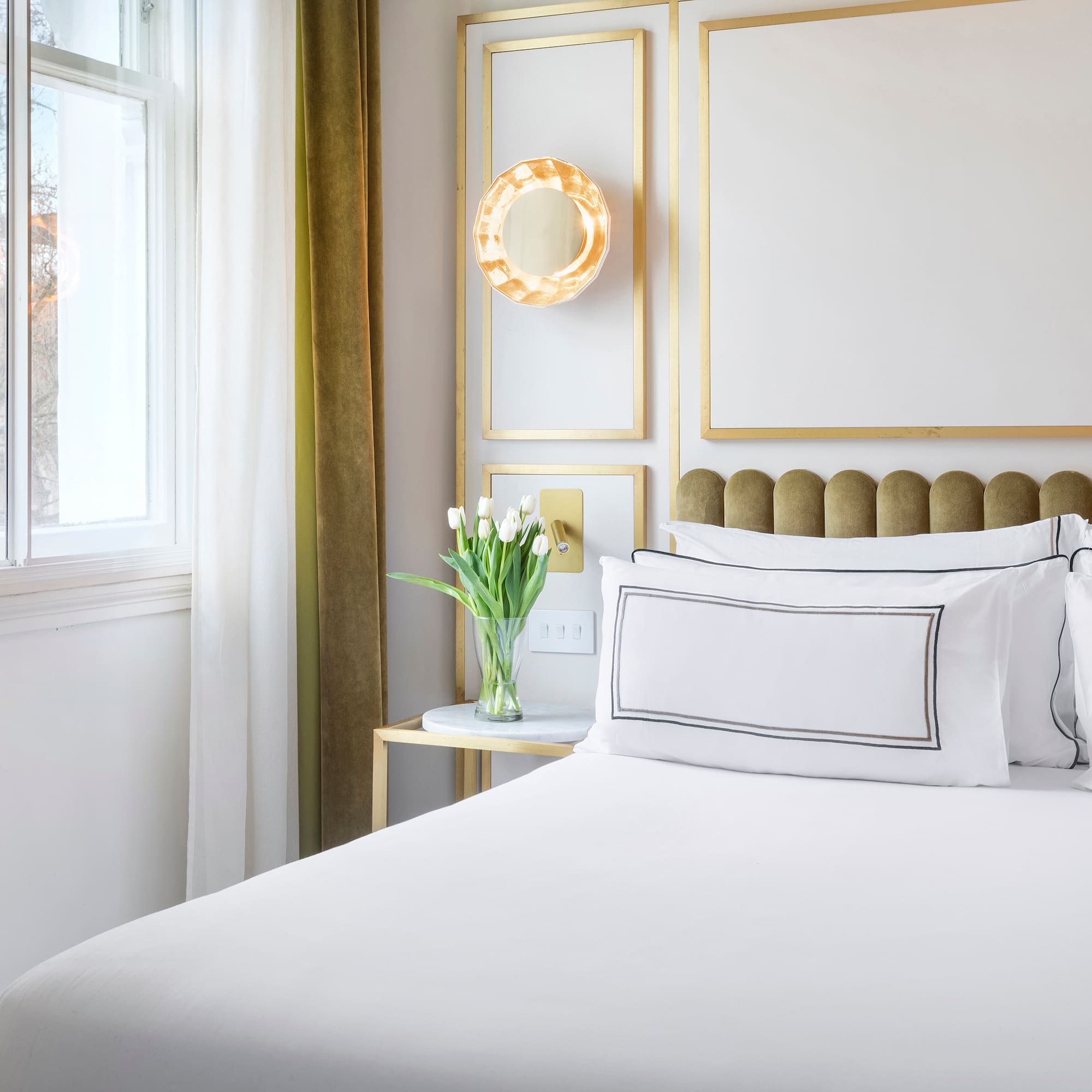 a bed with white sheets and pillows in a room with a window