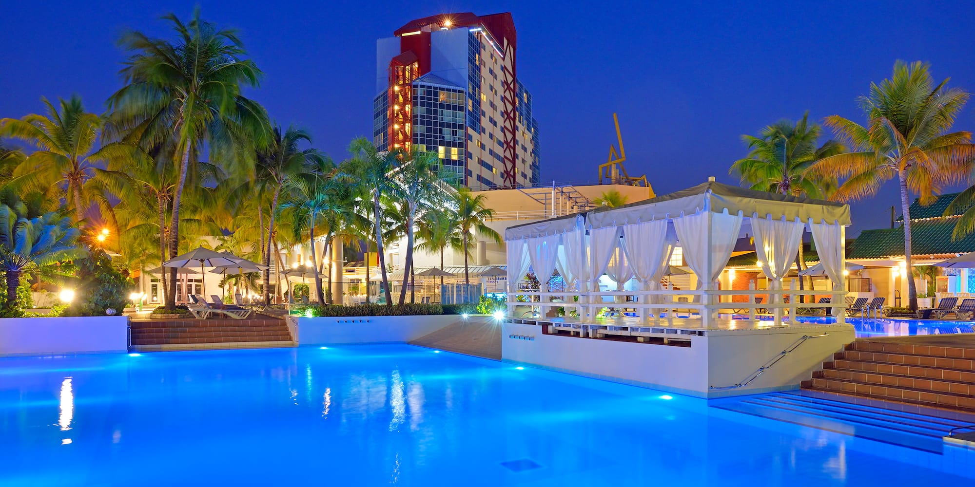 a pool with a gazebo and palm trees in the background