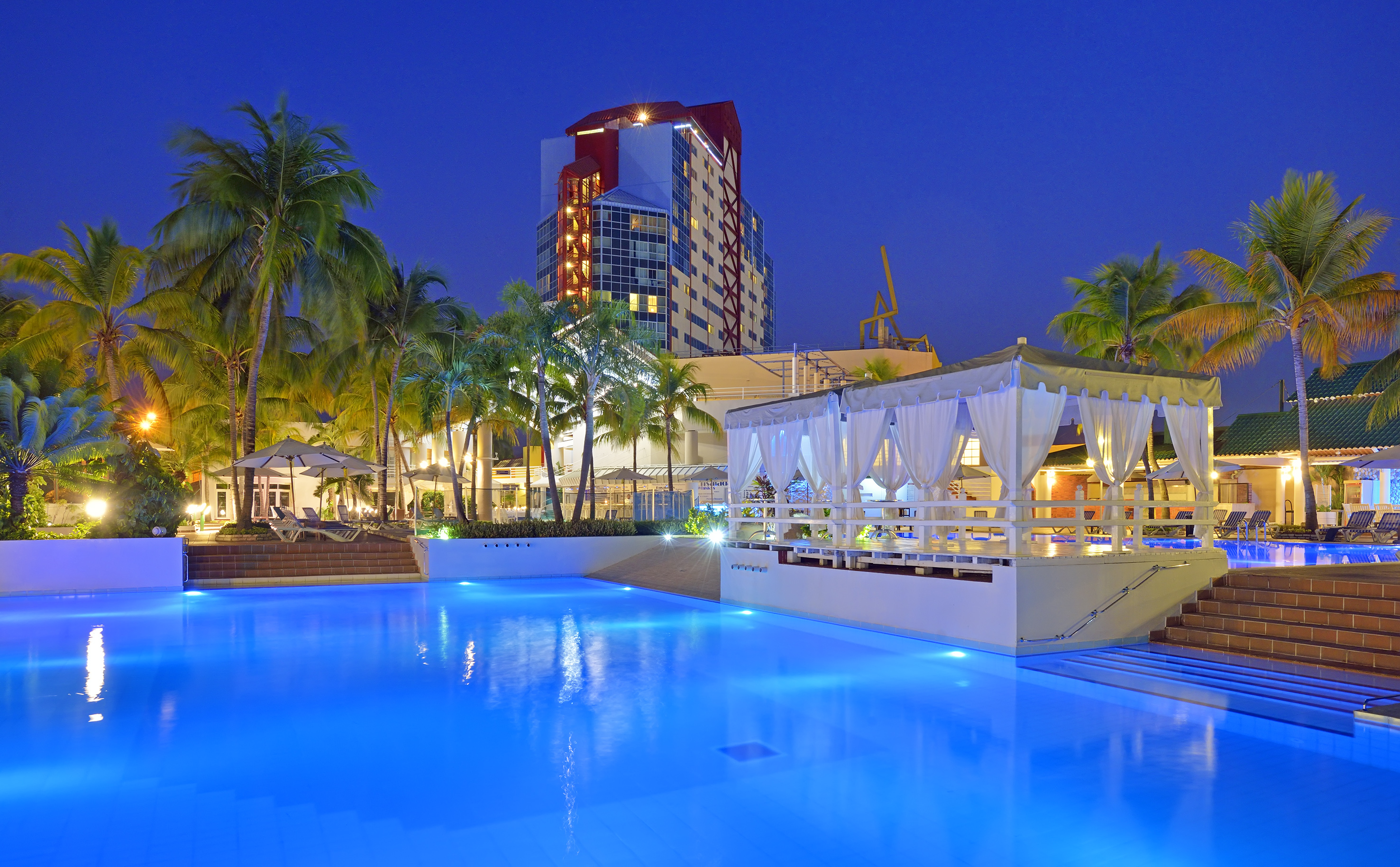 a pool with a gazebo and palm trees in the background