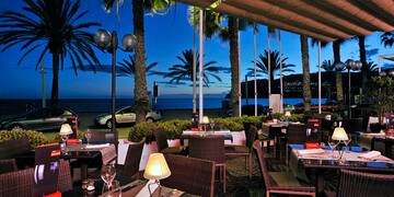 a restaurant with palm trees and a beach