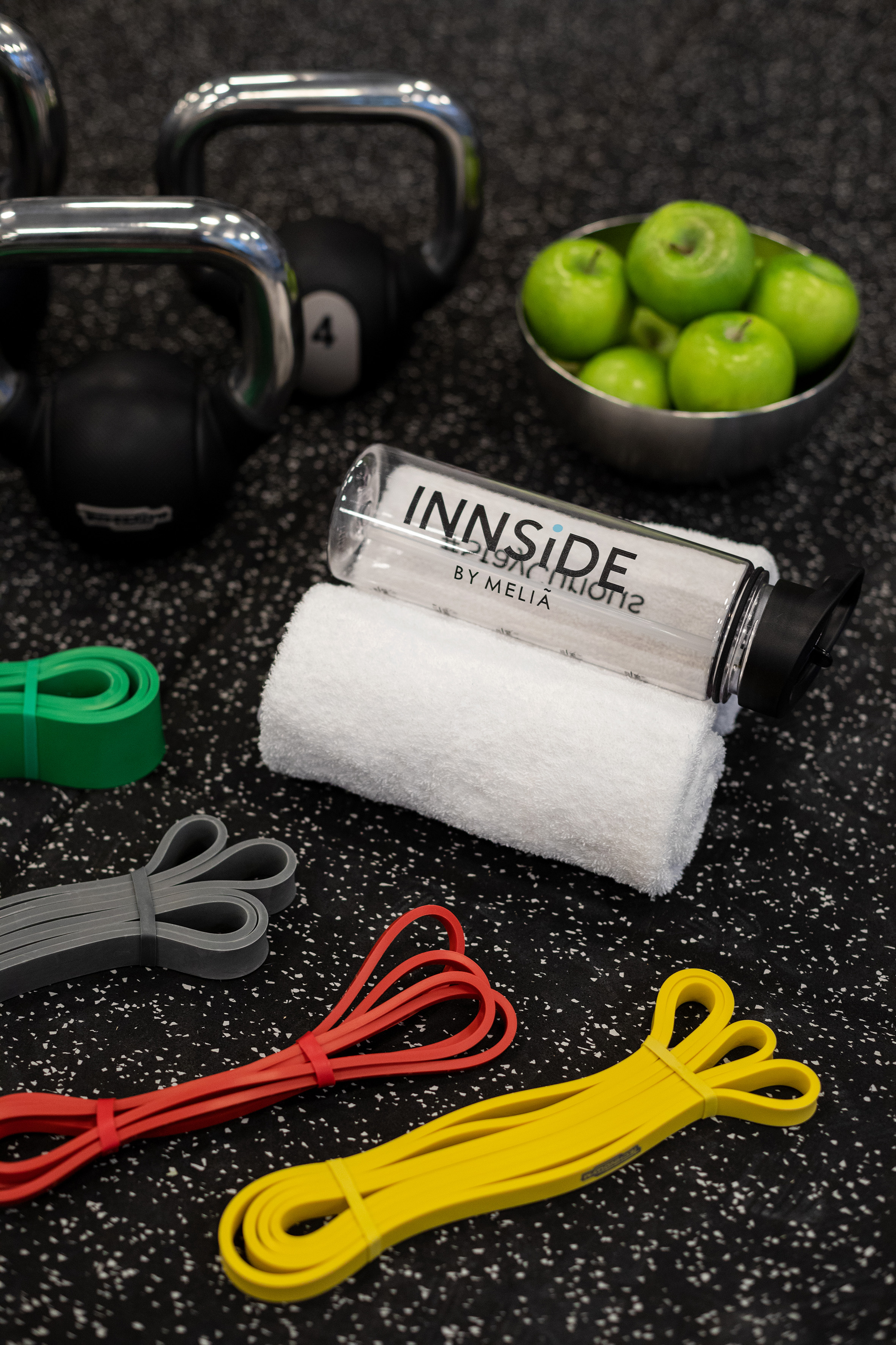 Kettlebells, resistance bands, INNSIDE bottle, towel, and green apples for fitness.