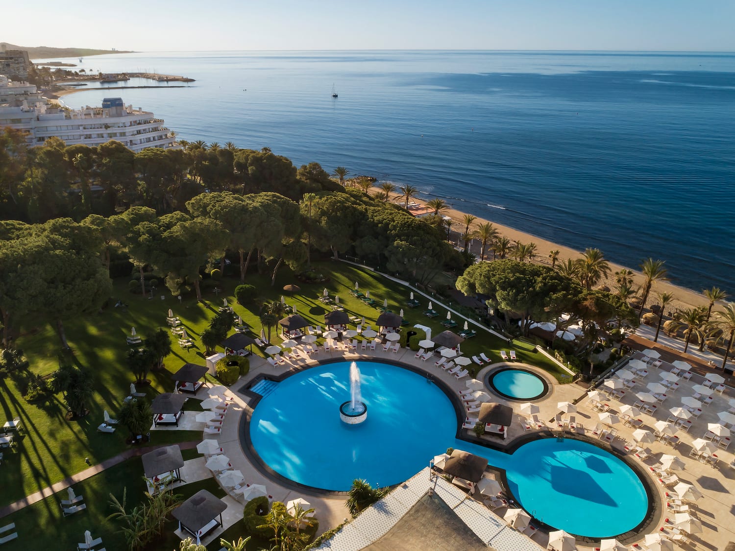 a pool with a fountain in the middle of a resort