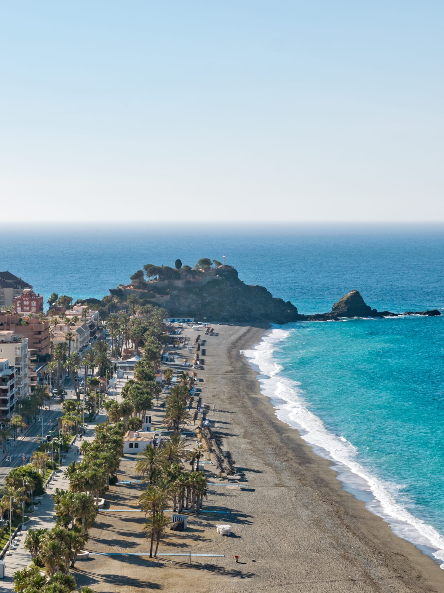 a beach with buildings and palm trees