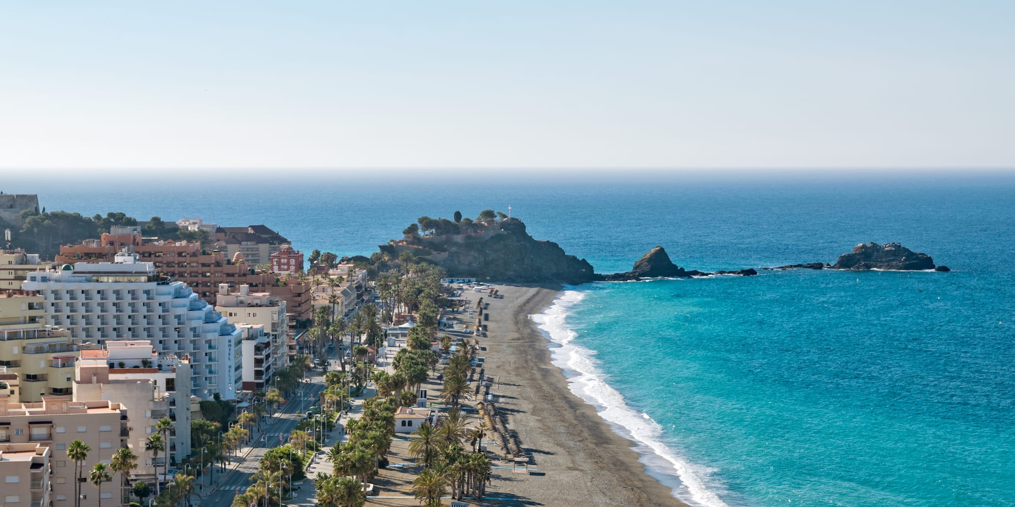 a beach with buildings and palm trees