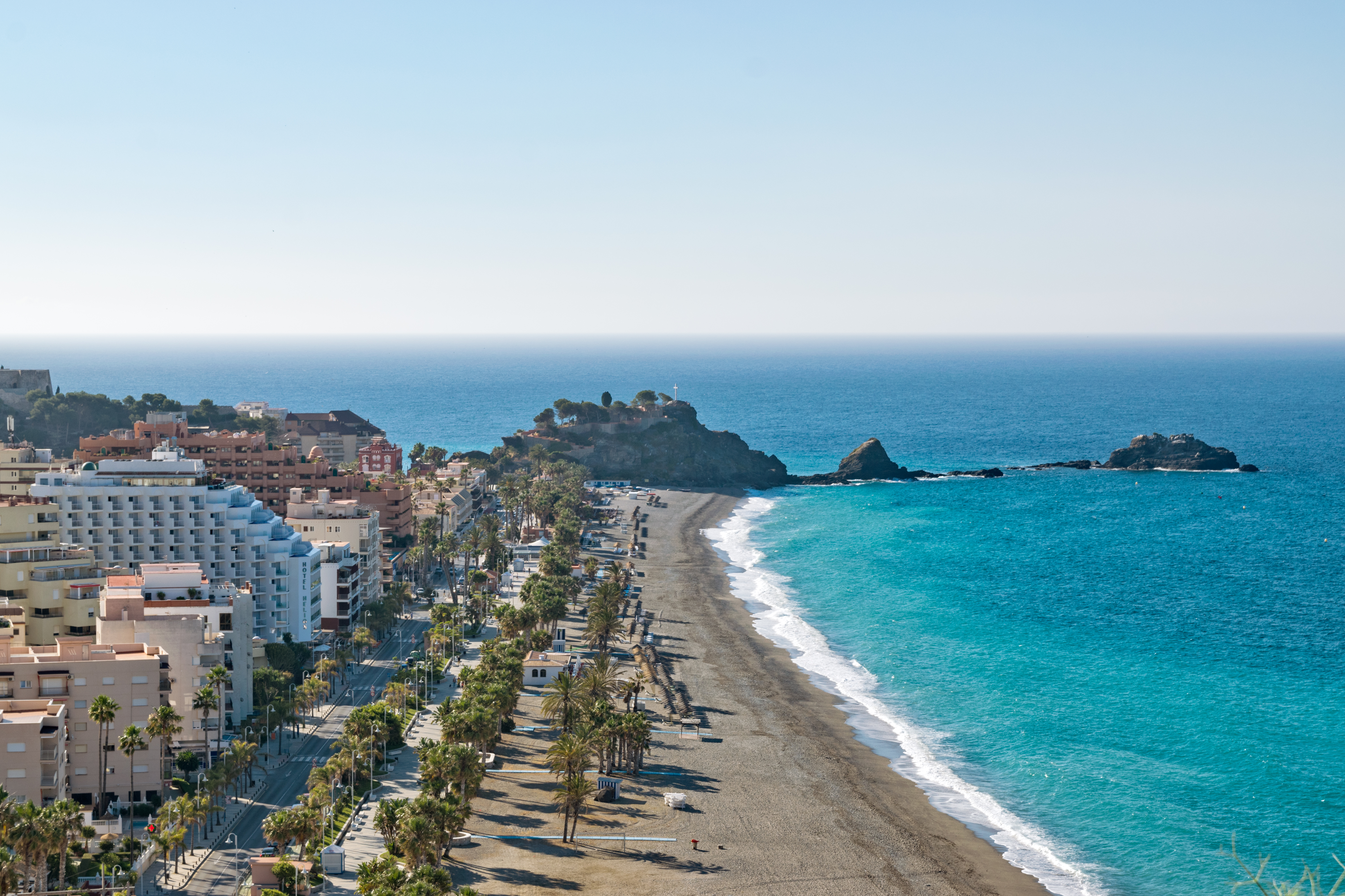 a beach with buildings and palm trees