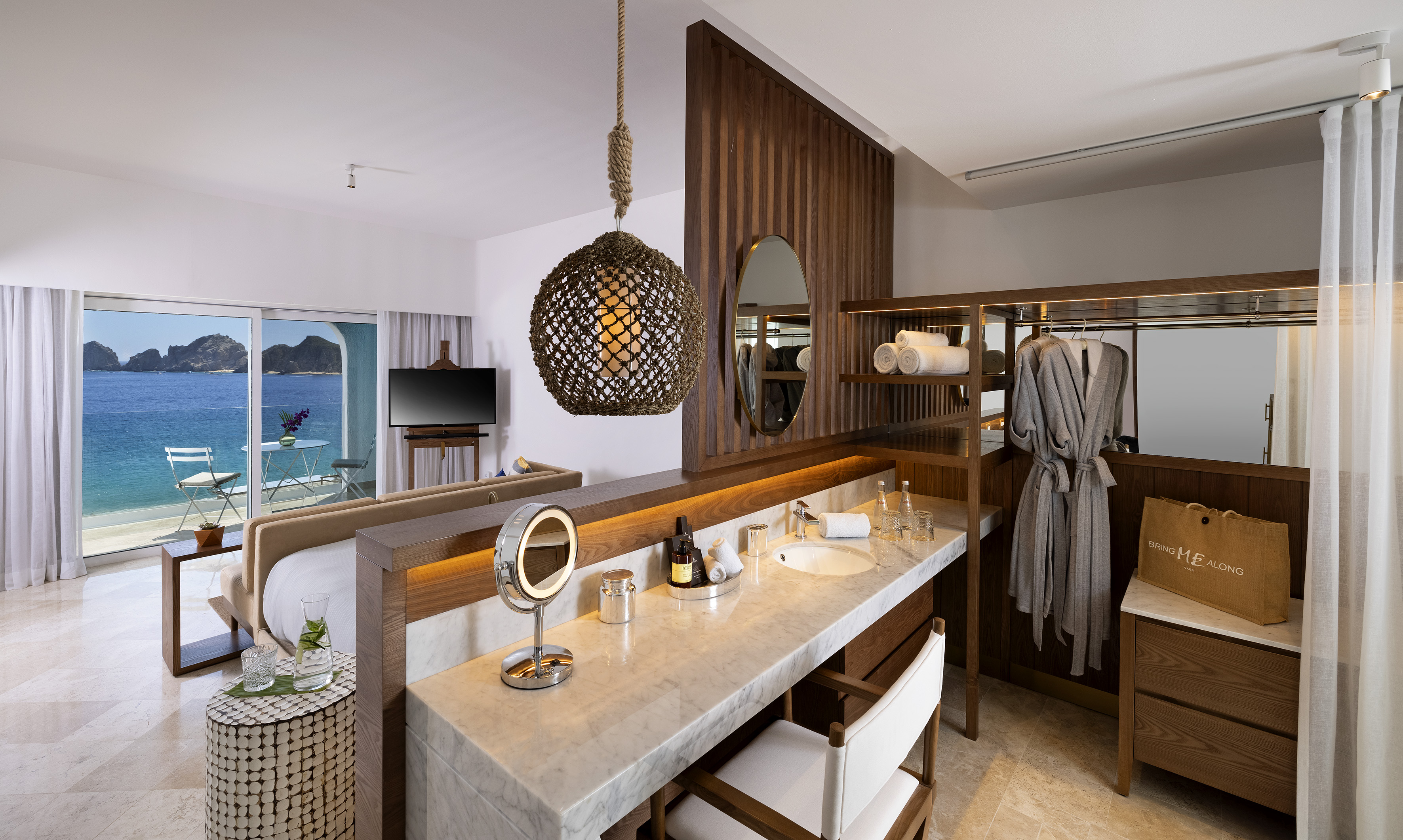 Coastal hotel suite with ocean view balcony, marble vanity, and lounge area.