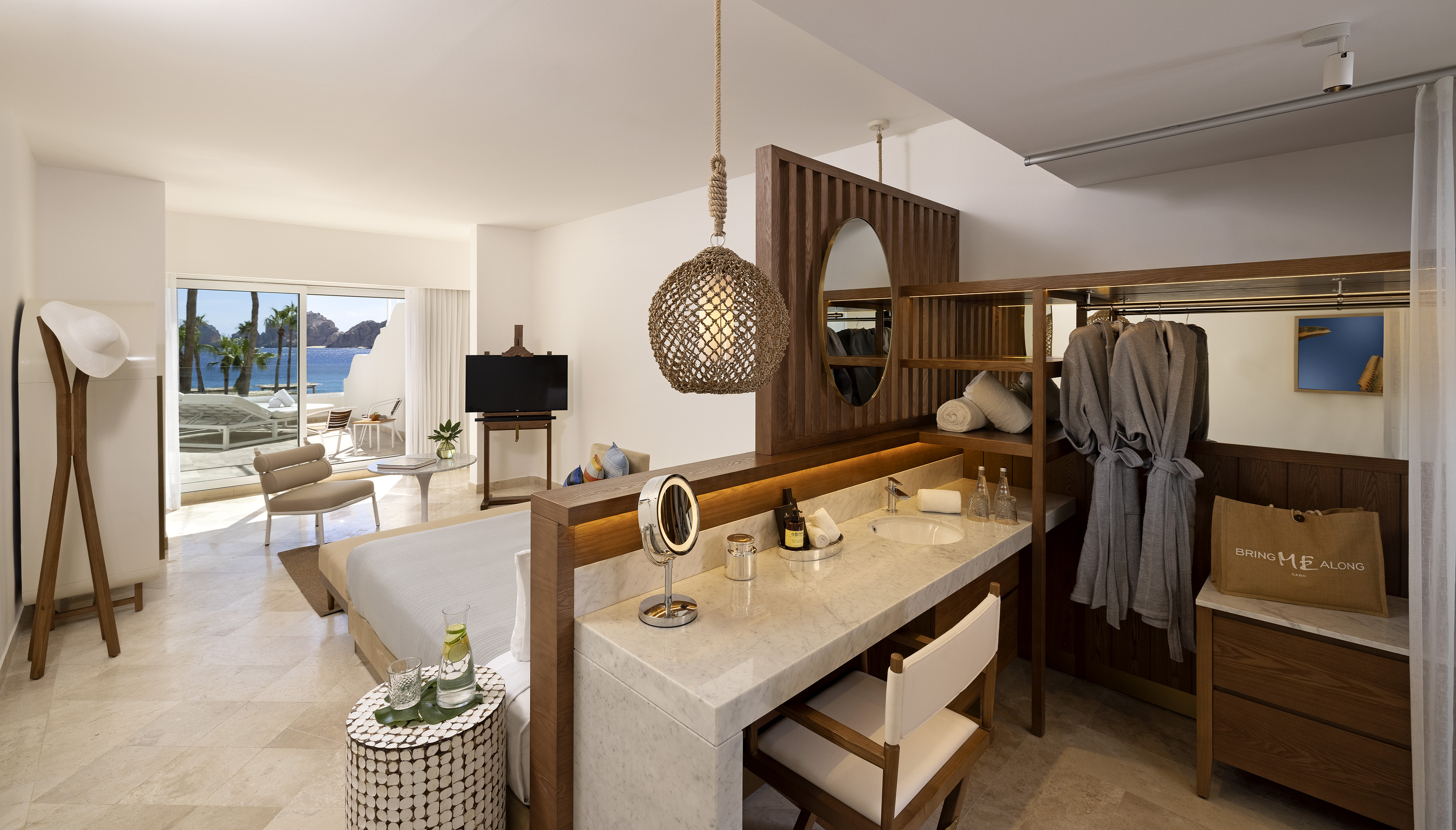 Luxury hotel suite with ocean view balcony, modern bedroom and vanity.