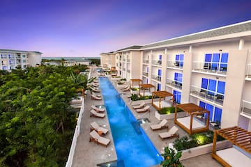 a pool with lounge chairs and trees in the background