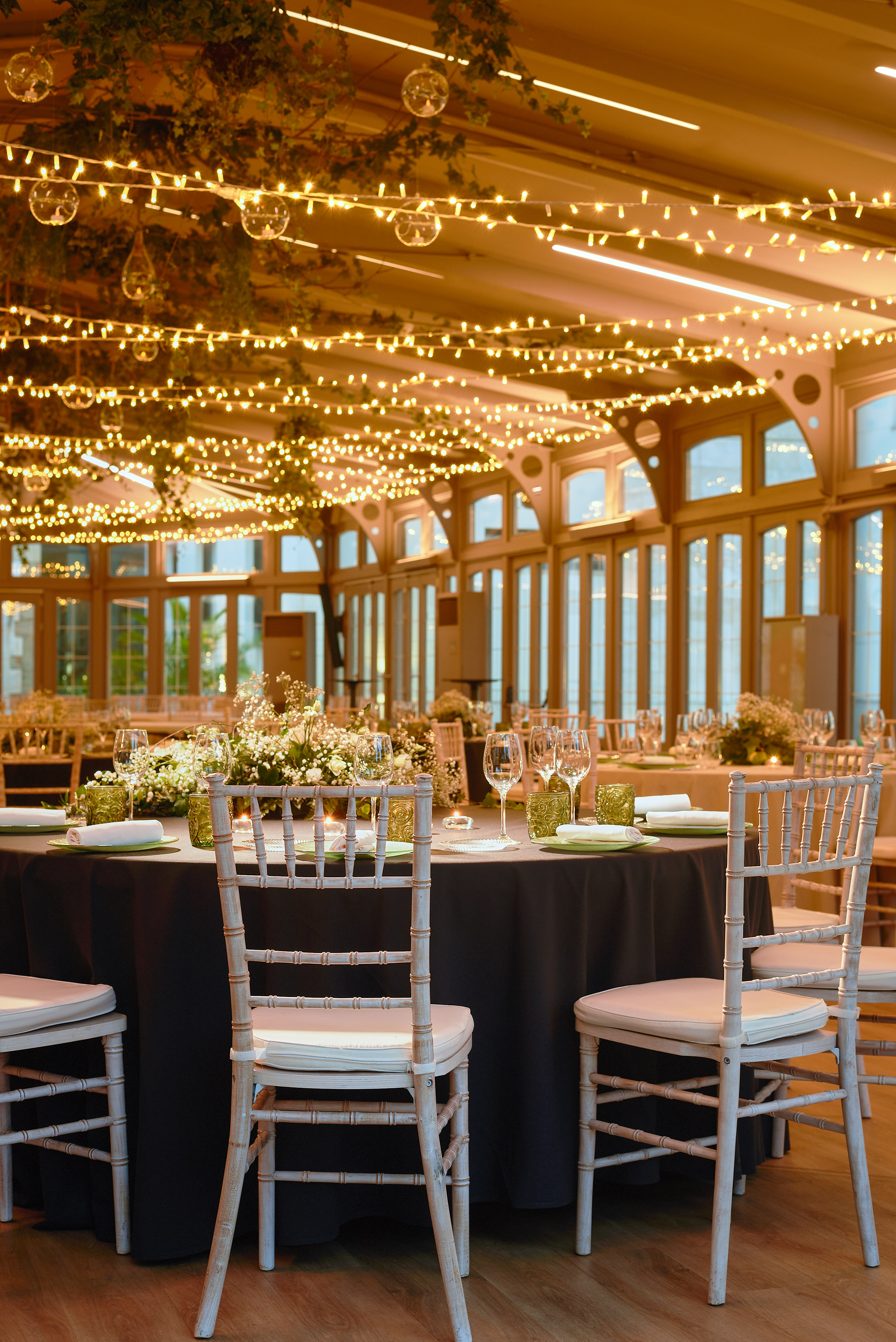 Event hall with warm fairy lights, floral decor, and elegant dining tables. - Invernadero - Palacio de Avilés Affiliated by Meliá, Avilés