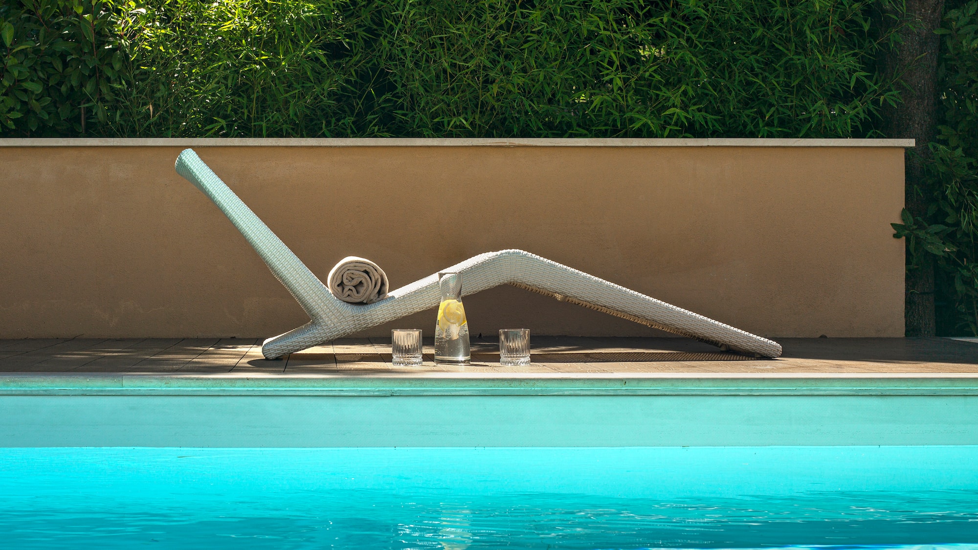a pool with a white chair and glasses on the side