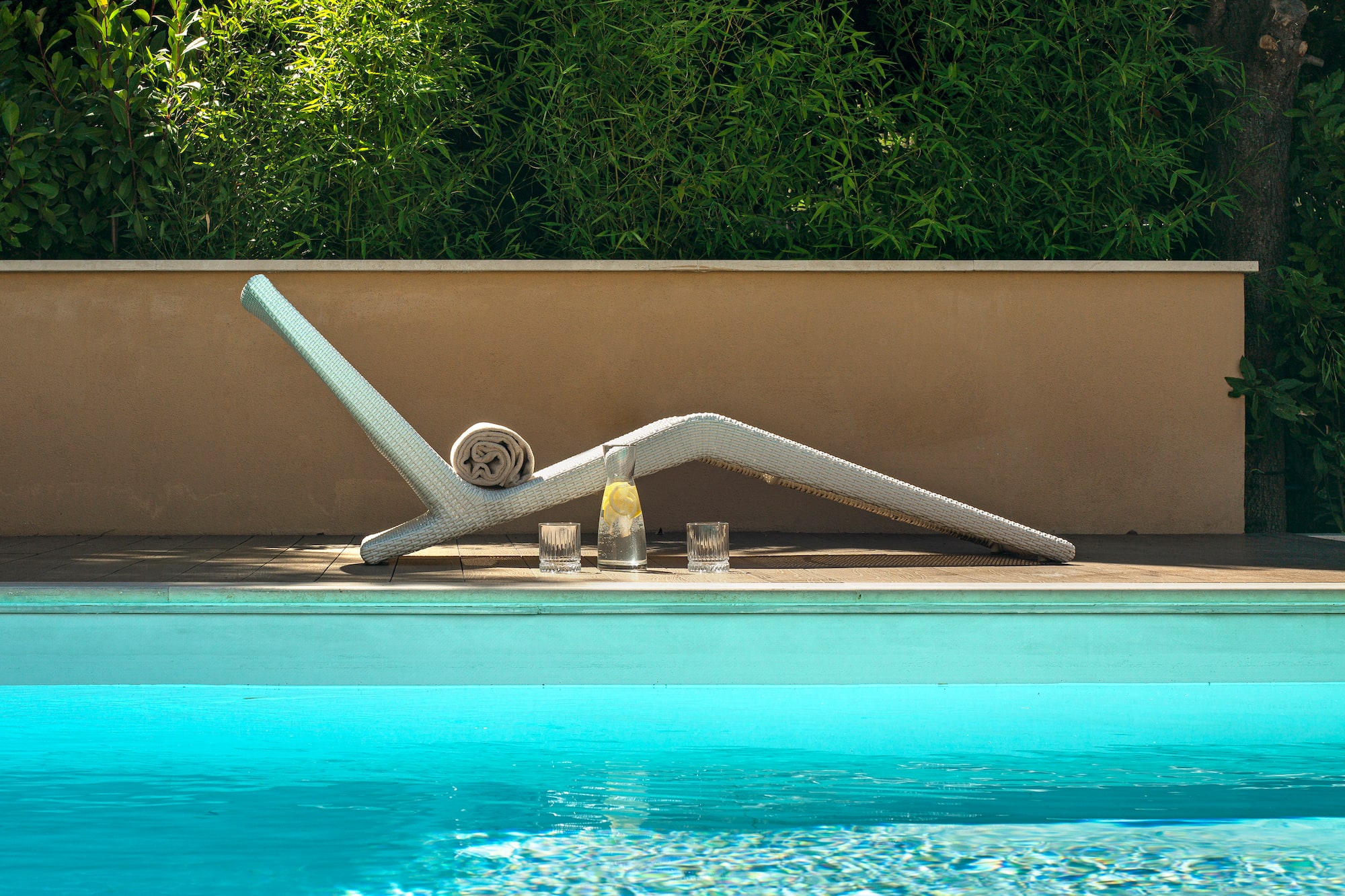 a pool with a white chair and glasses on the side