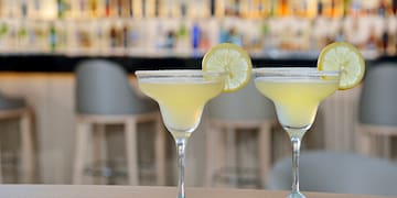 two glasses of yellow liquid with lemon slices on top of them