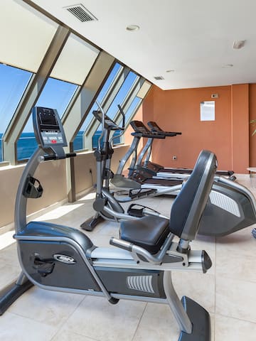 a room with exercise bikes and a window overlooking the ocean