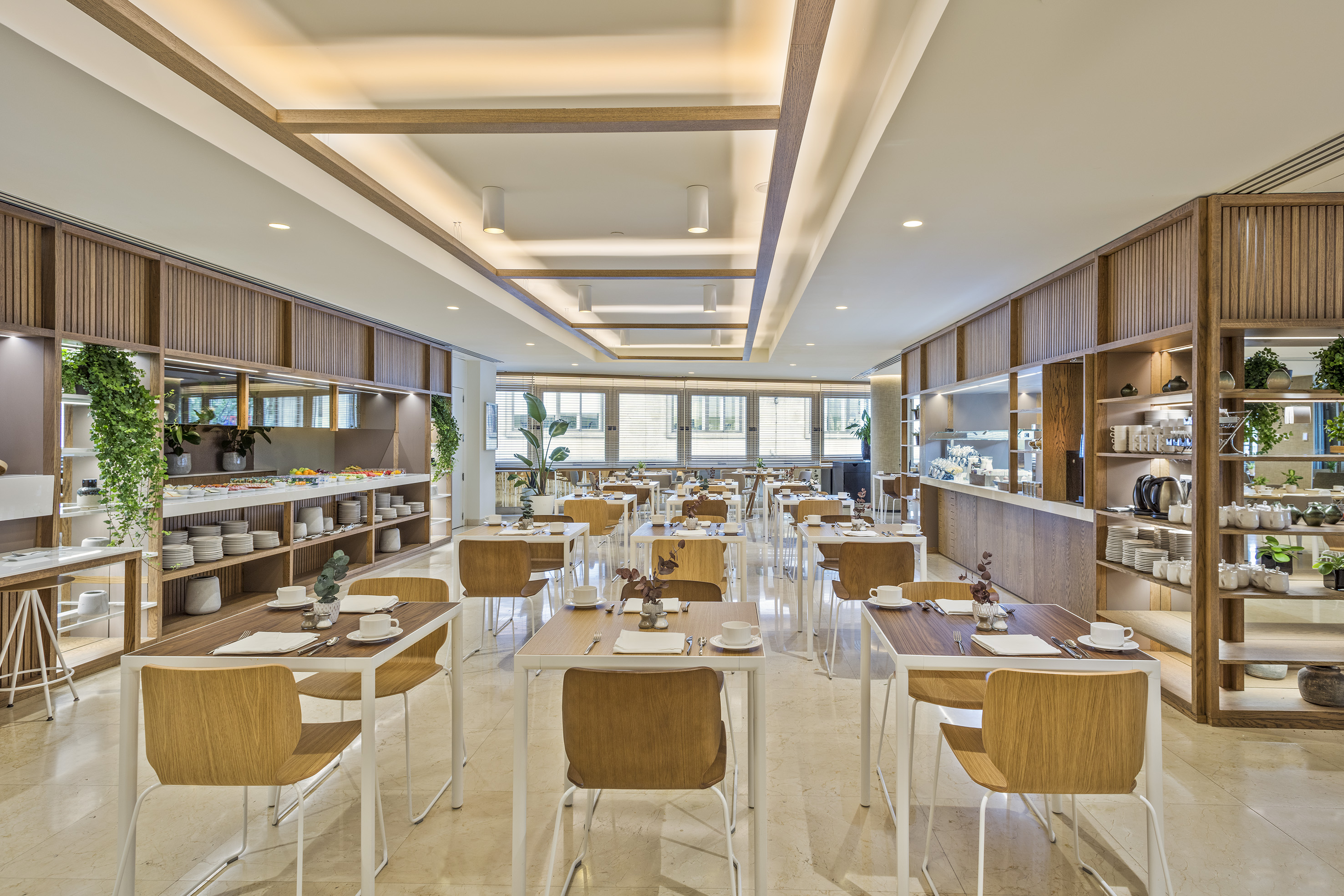 Spacious hotel breakfast buffet and dining area with modern wooden tables.