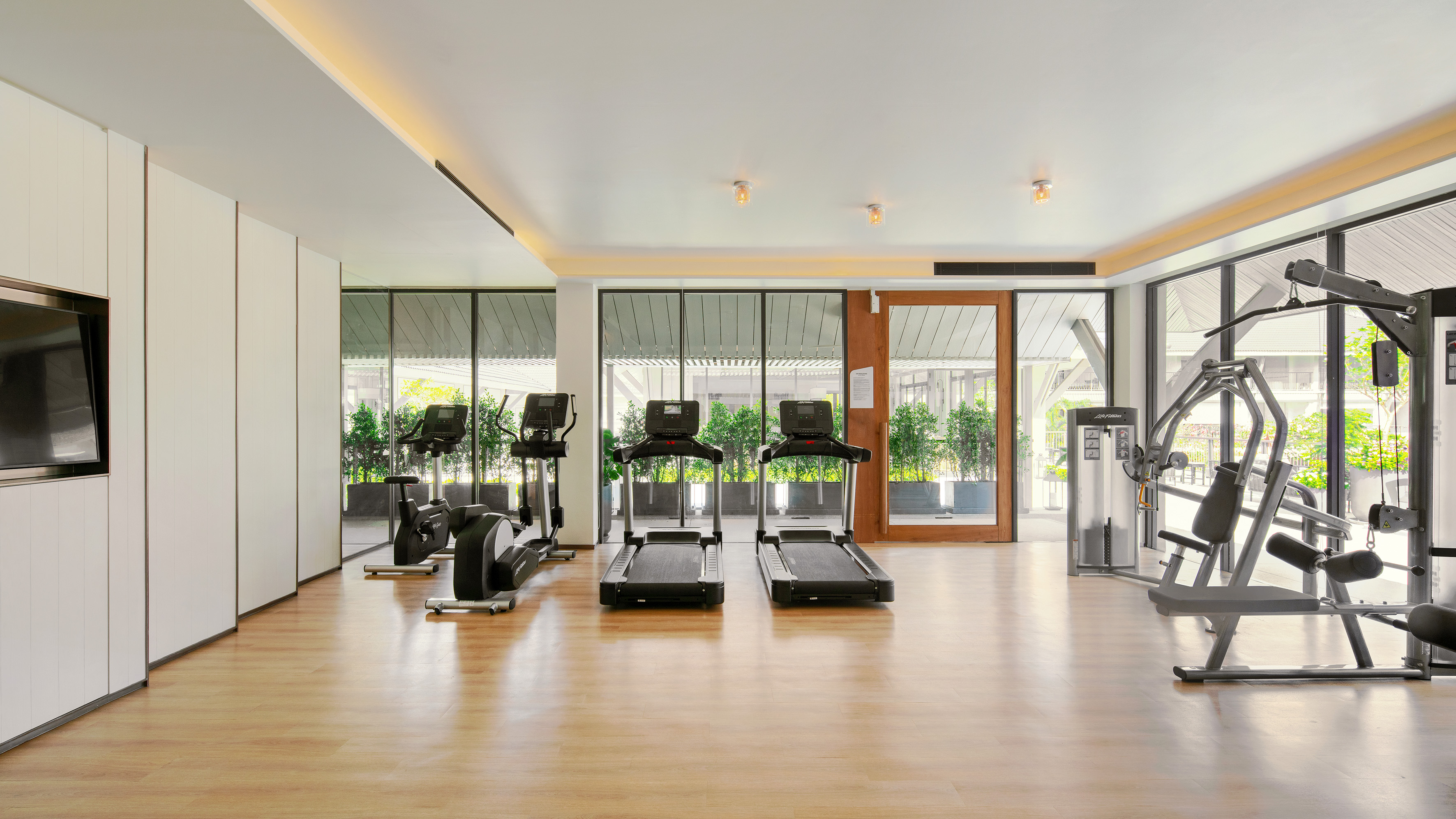 Bright, modern hotel gym featuring treadmills, elliptical, and weight machine.