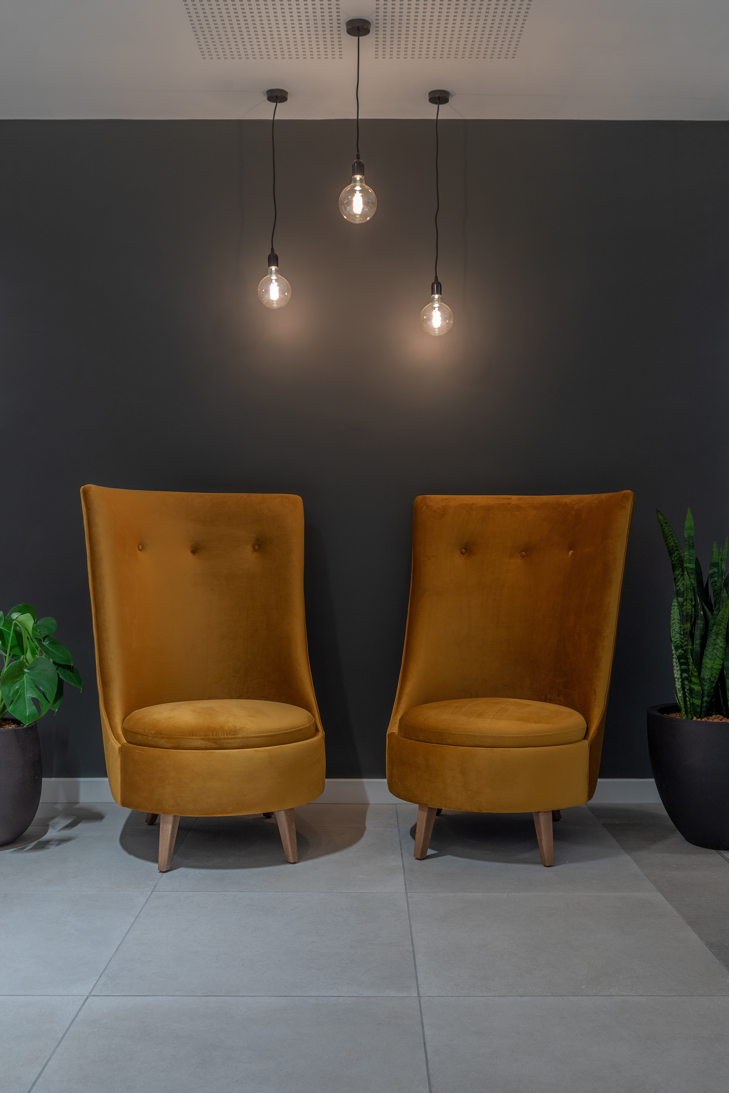 Mustard velvet armchairs, exposed bulb pendant lights, modern interior design.
