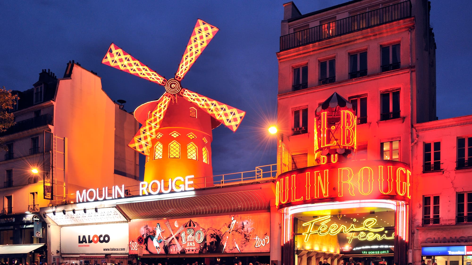 Moulin Rouge with a windmill on top and people standing in front of it
