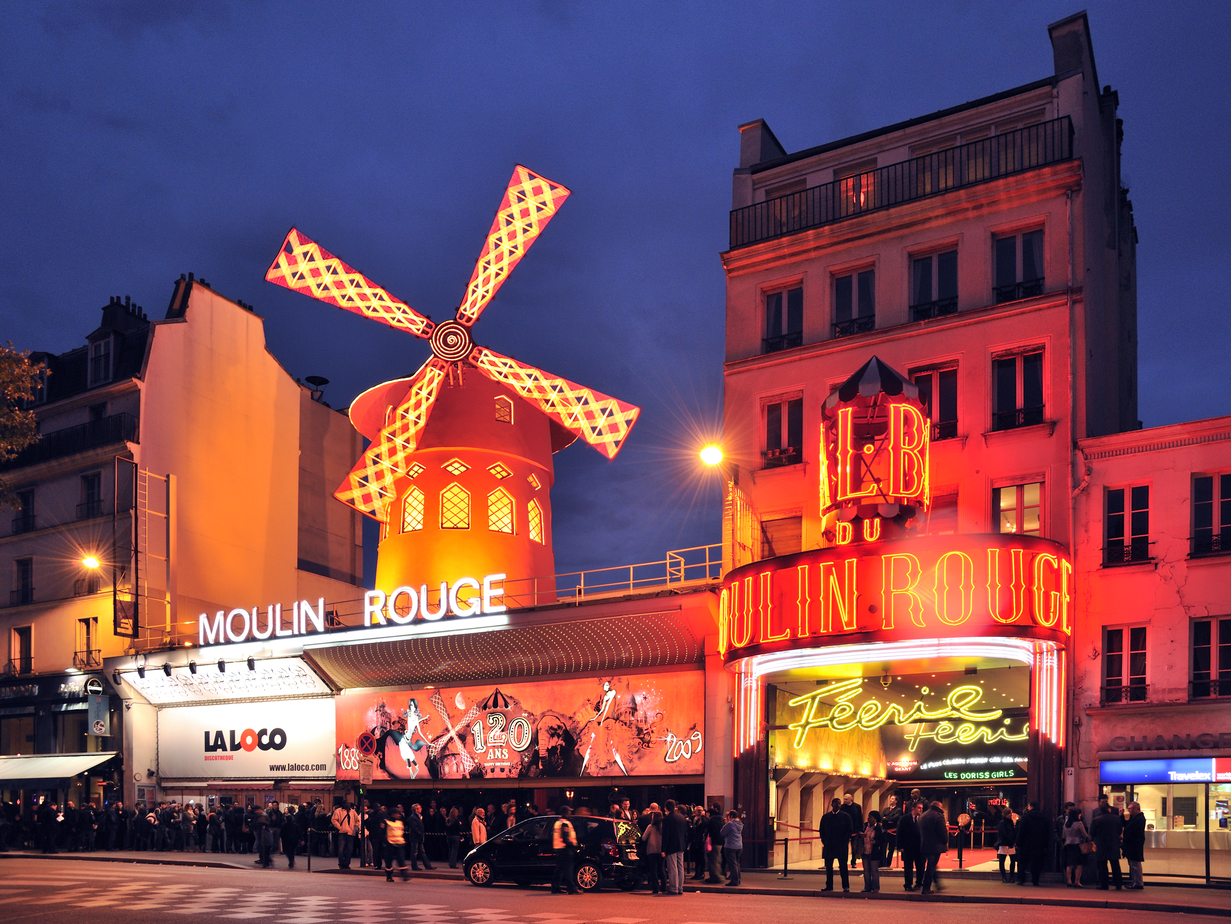 Moulin Rouge with a windmill on top and people standing in front of it