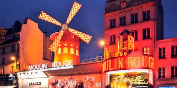 Moulin Rouge with a windmill on top and people standing in front of it