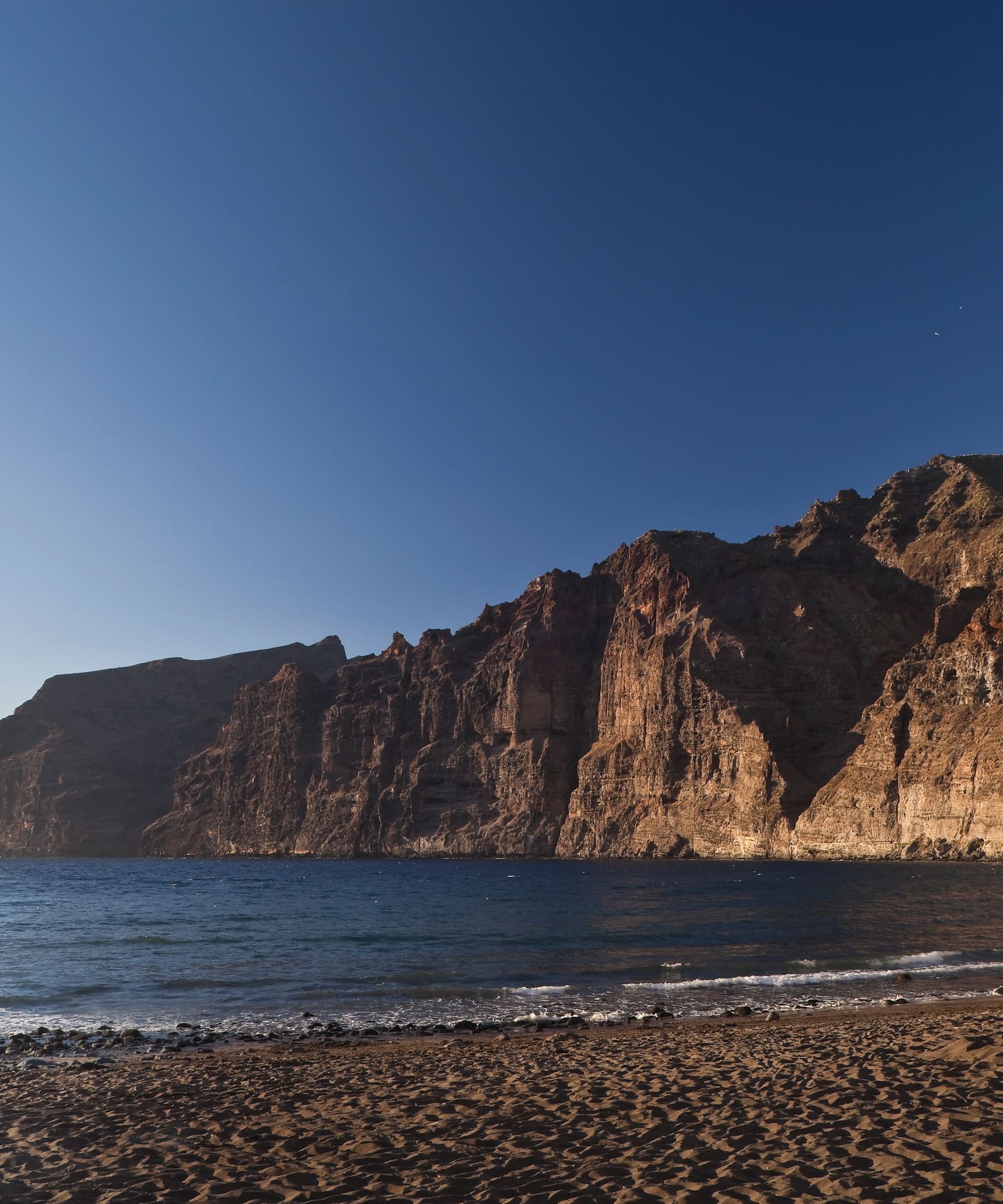 Acantilados de Los Gigantes, playa de arena negra y mar azul, Tenerife.