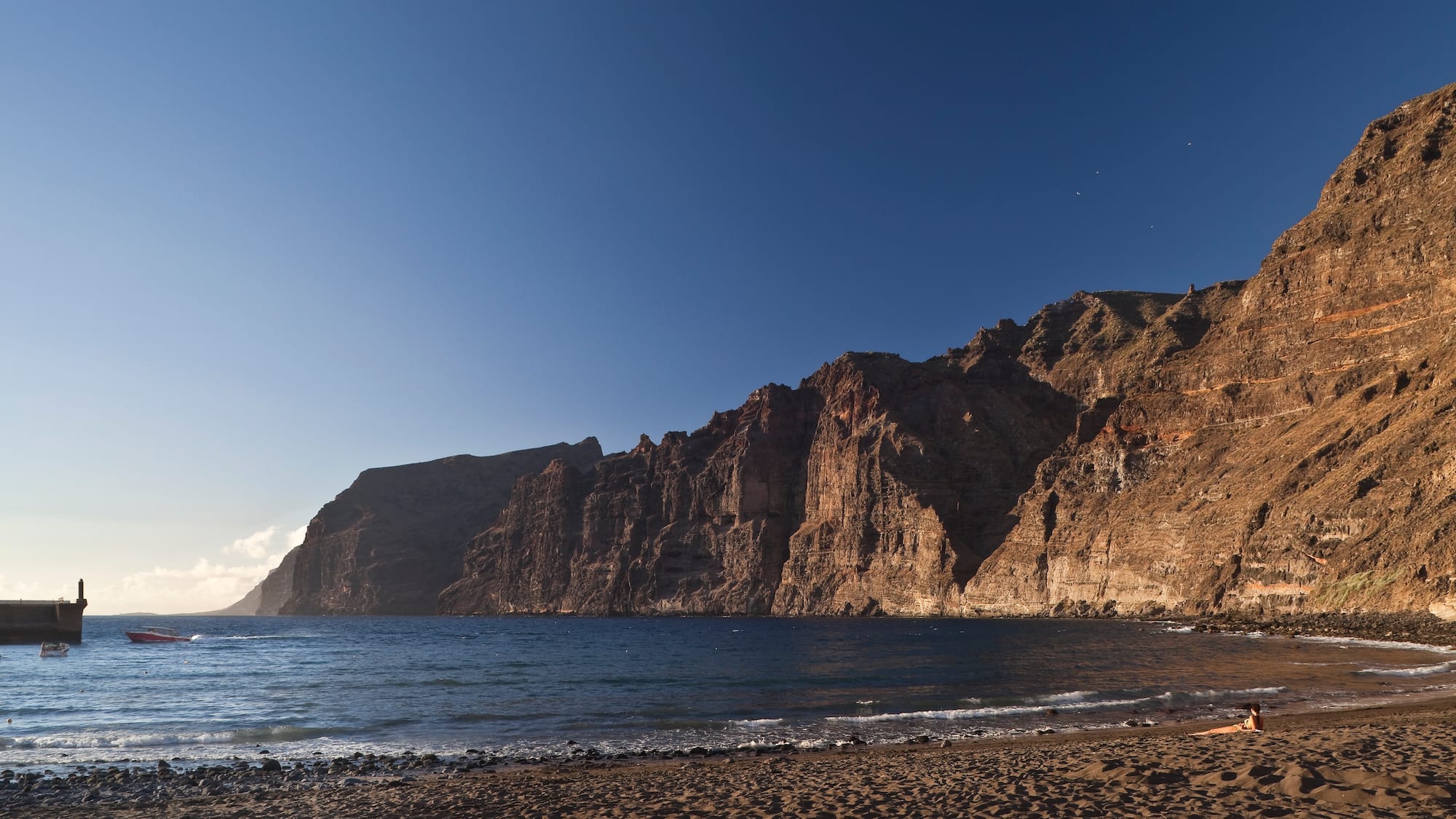 a beach with a body of water and a rocky cliff