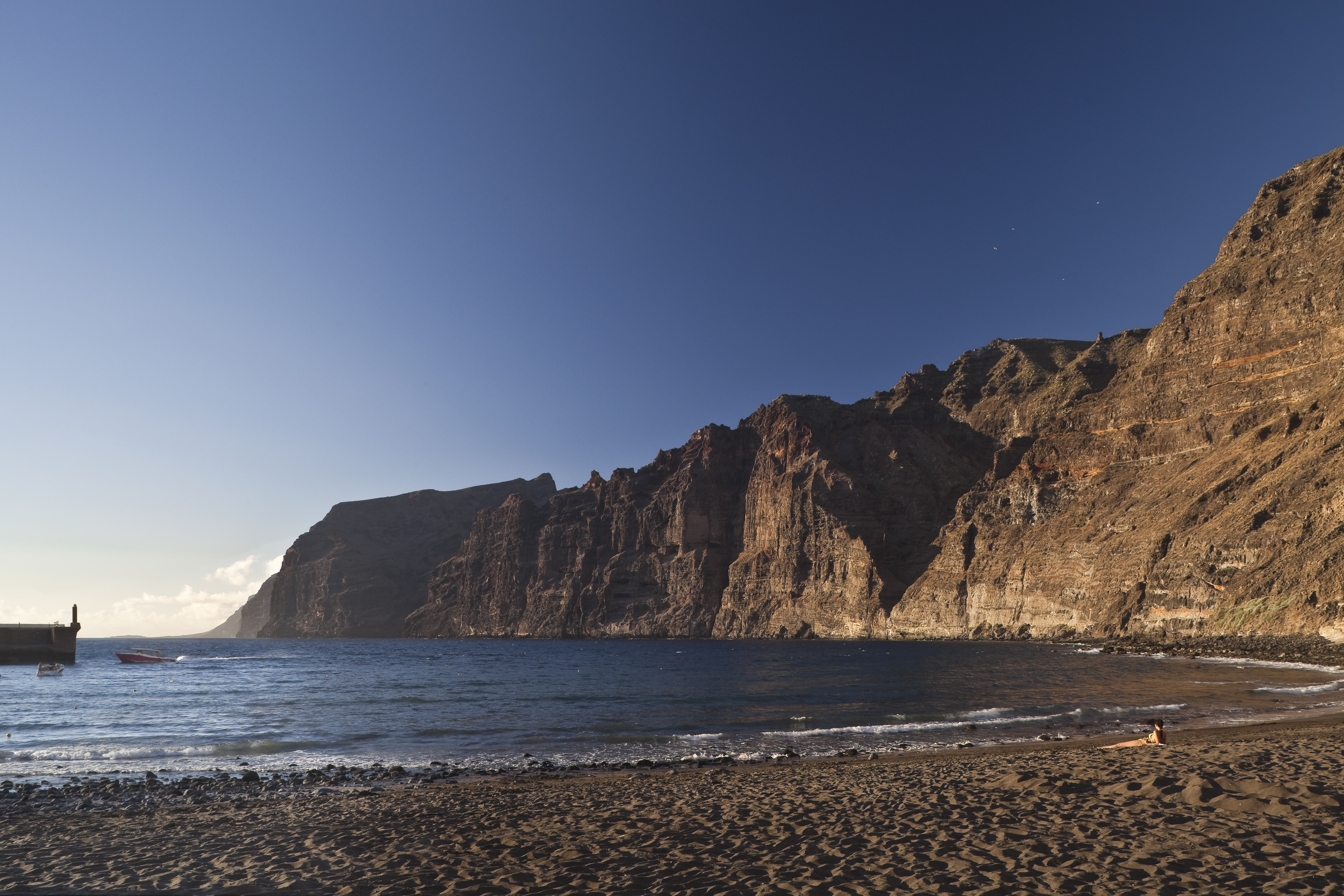 a beach with a body of water and a rocky cliff