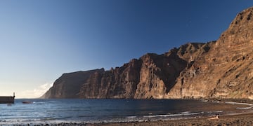 a beach with a body of water and a rocky cliff