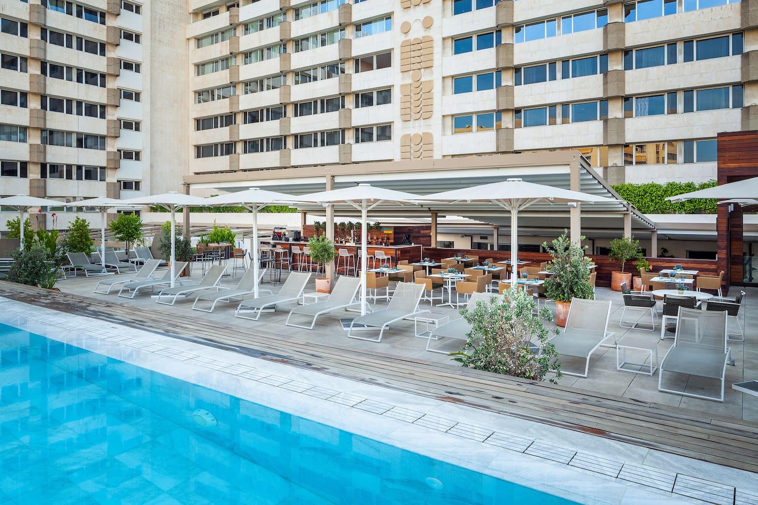a pool with chairs and umbrellas in front of a building