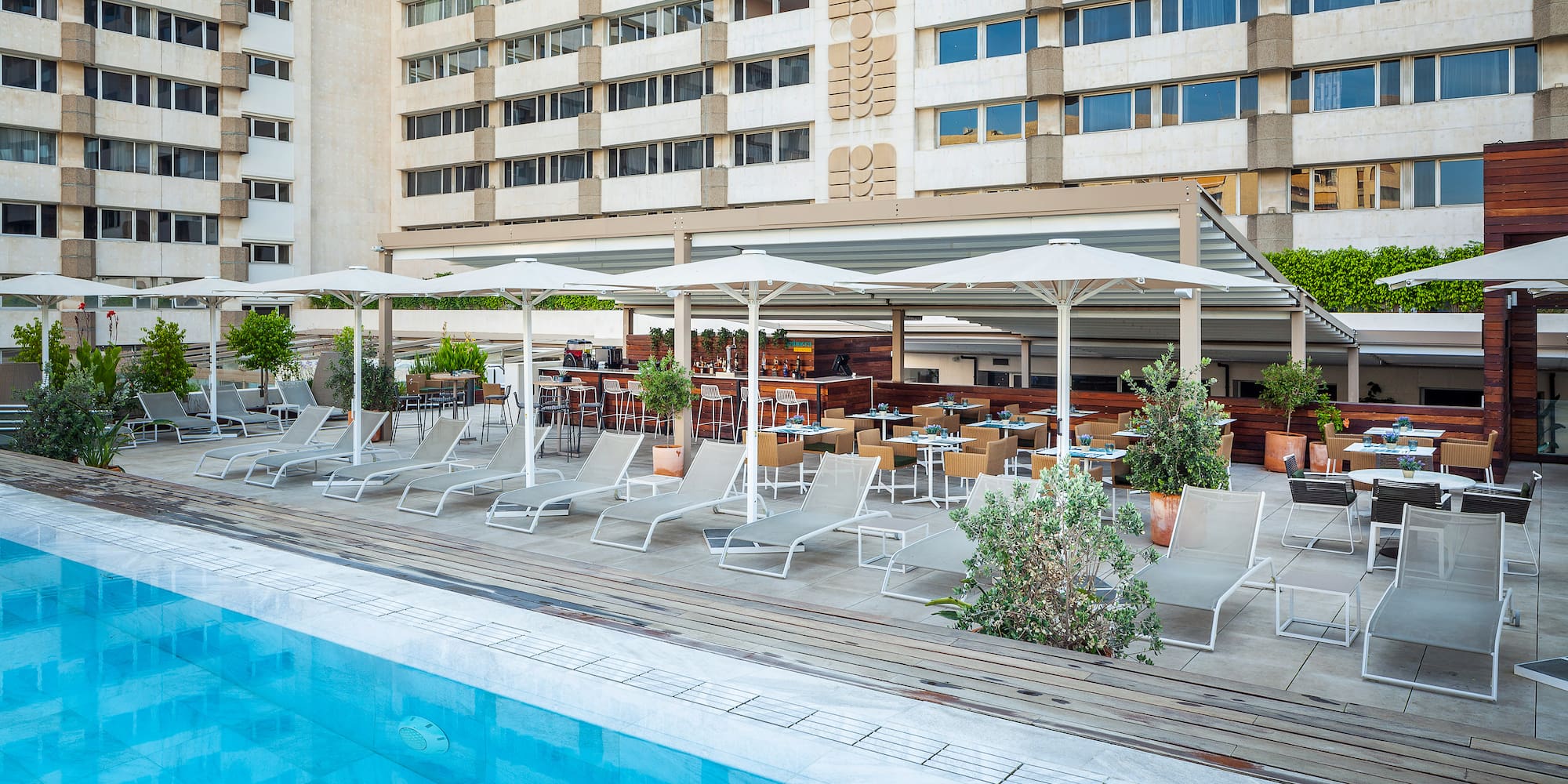 a pool with chairs and umbrellas in front of a building