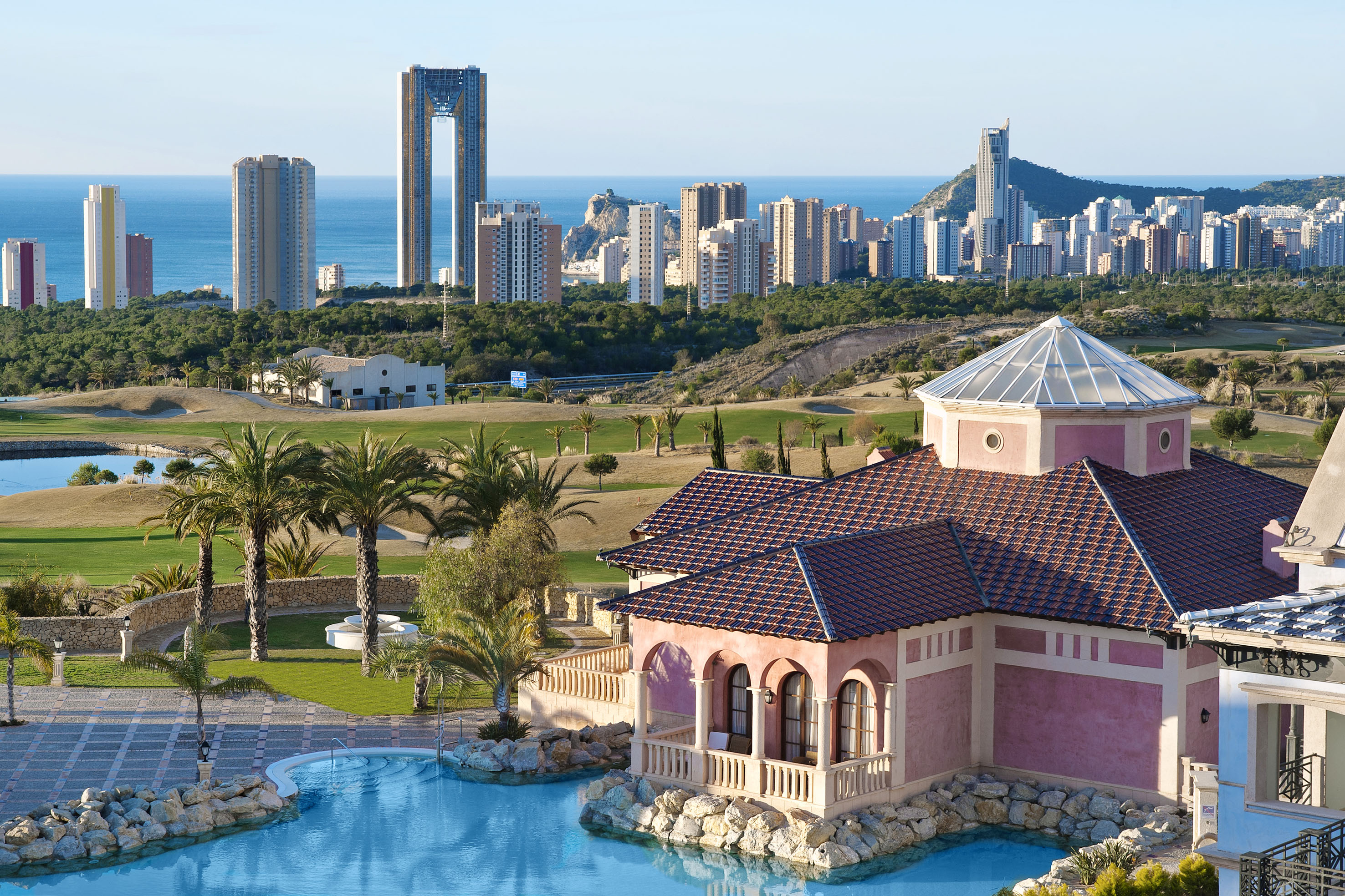 Benidorm resort villa, pool, golf course, and coastal city skyline.