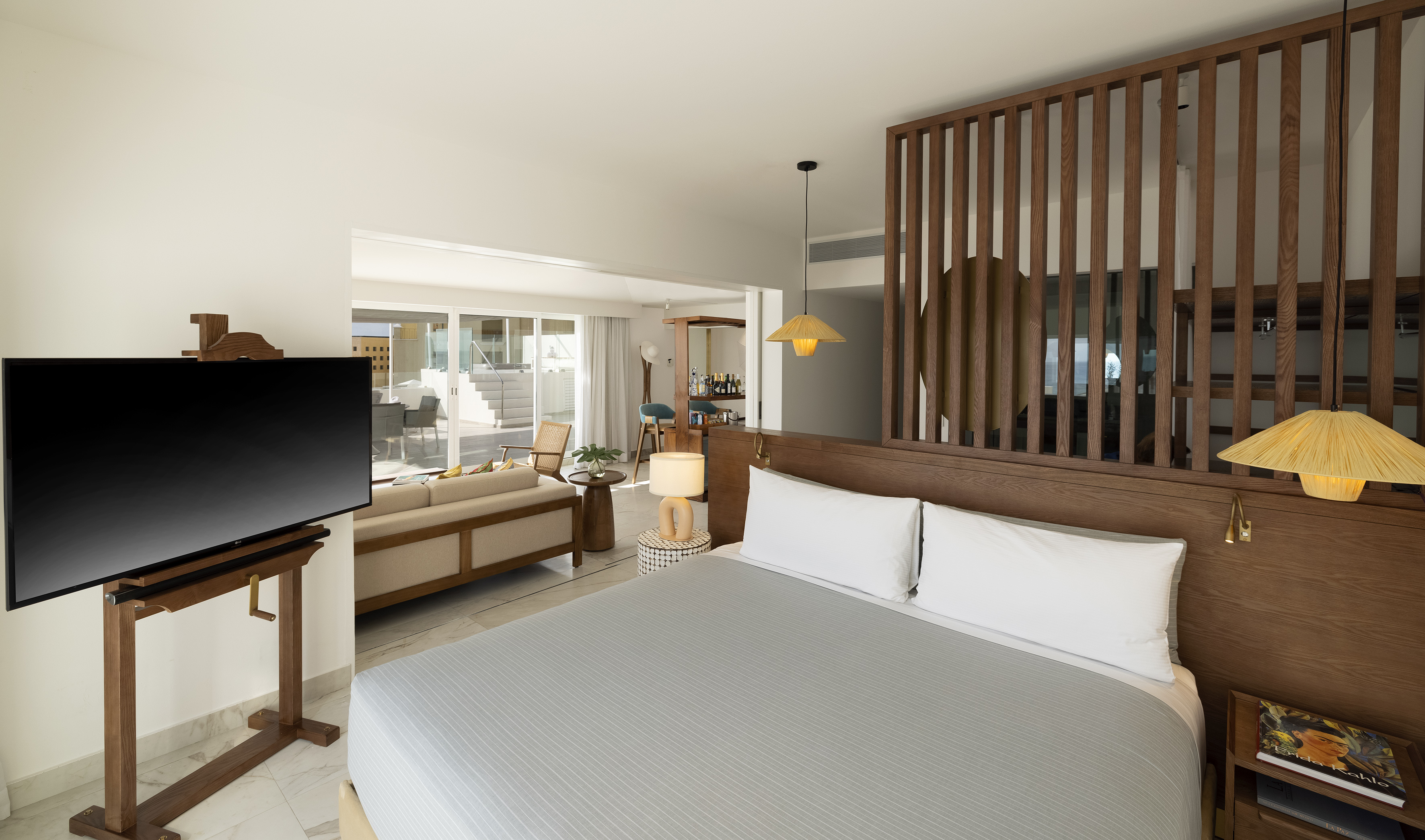 Luxury hotel bedroom suite with open living area, modern TV, and patio access.