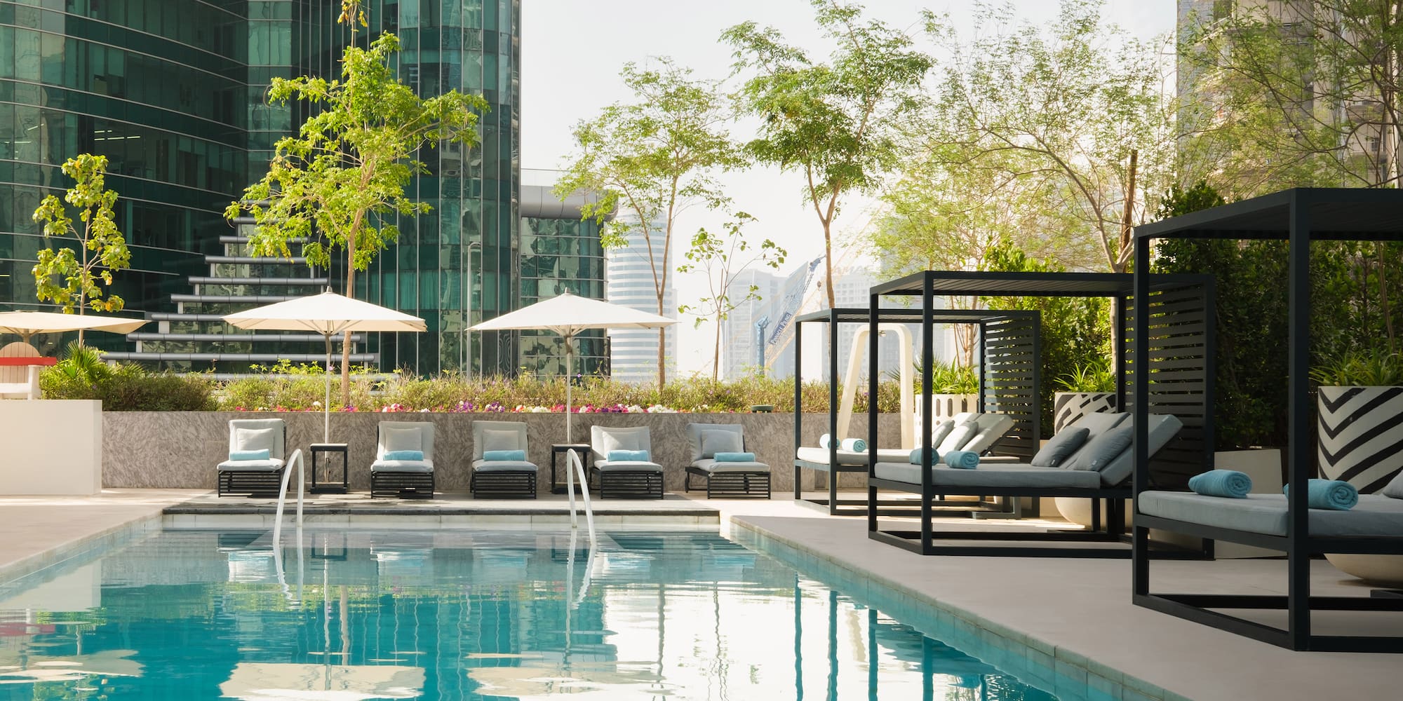 a pool with chairs and umbrellas in front of a building