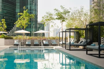 a pool with chairs and umbrellas in front of a building