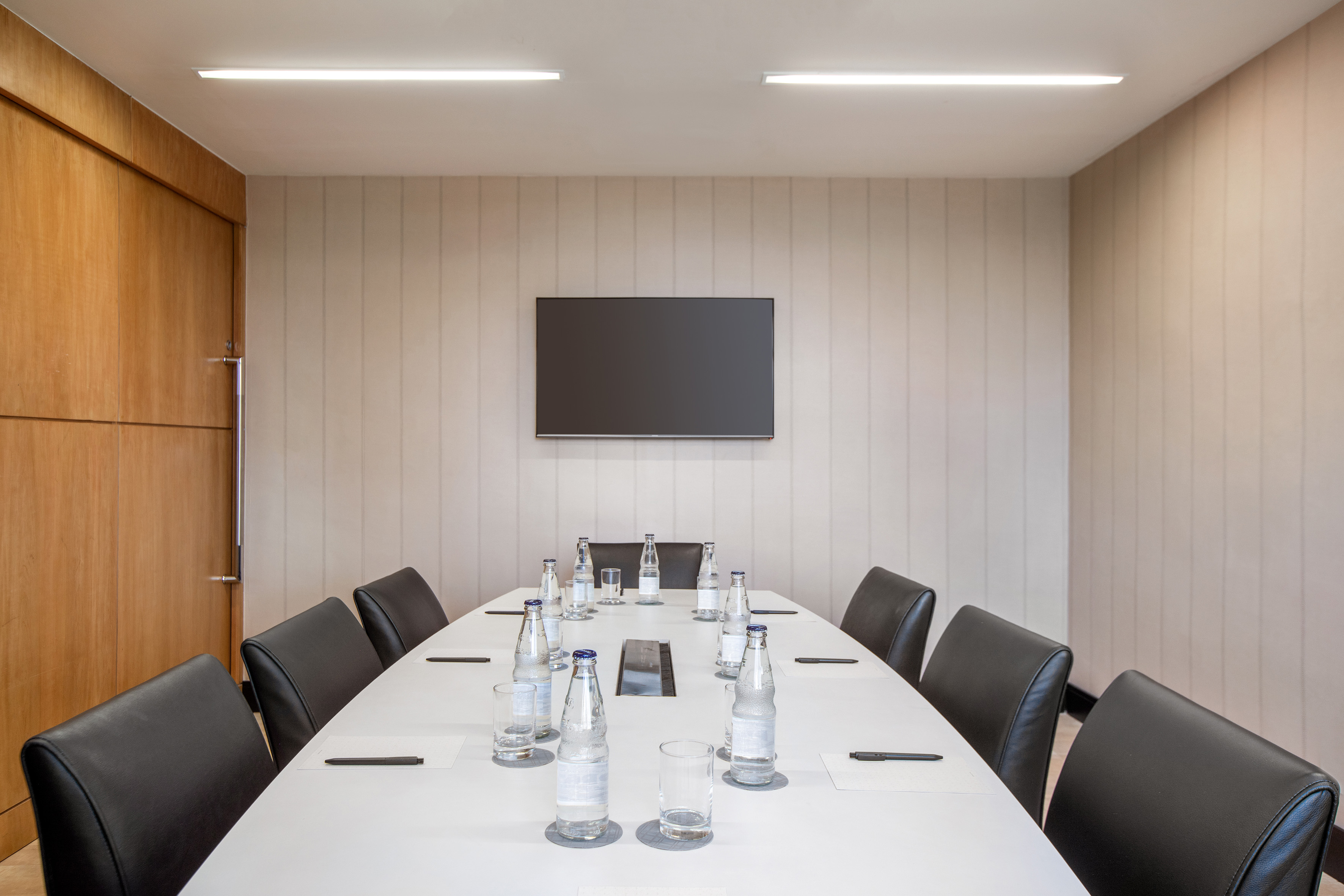 Sleek modern meeting room with large table, executive chairs, and flat-screen TV.