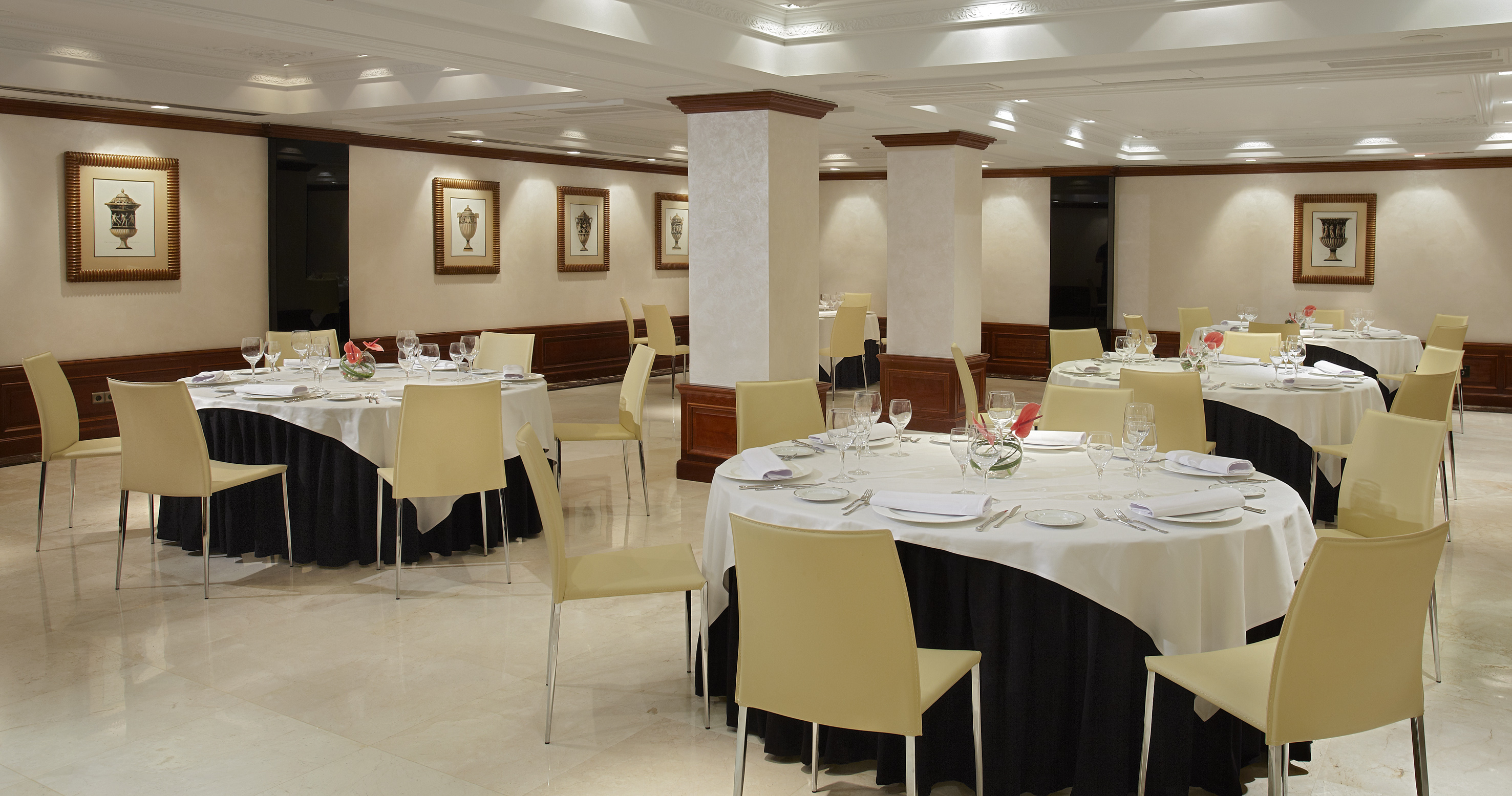 Elegant dining room with formal round tables, cream chairs, and neutral decor.
