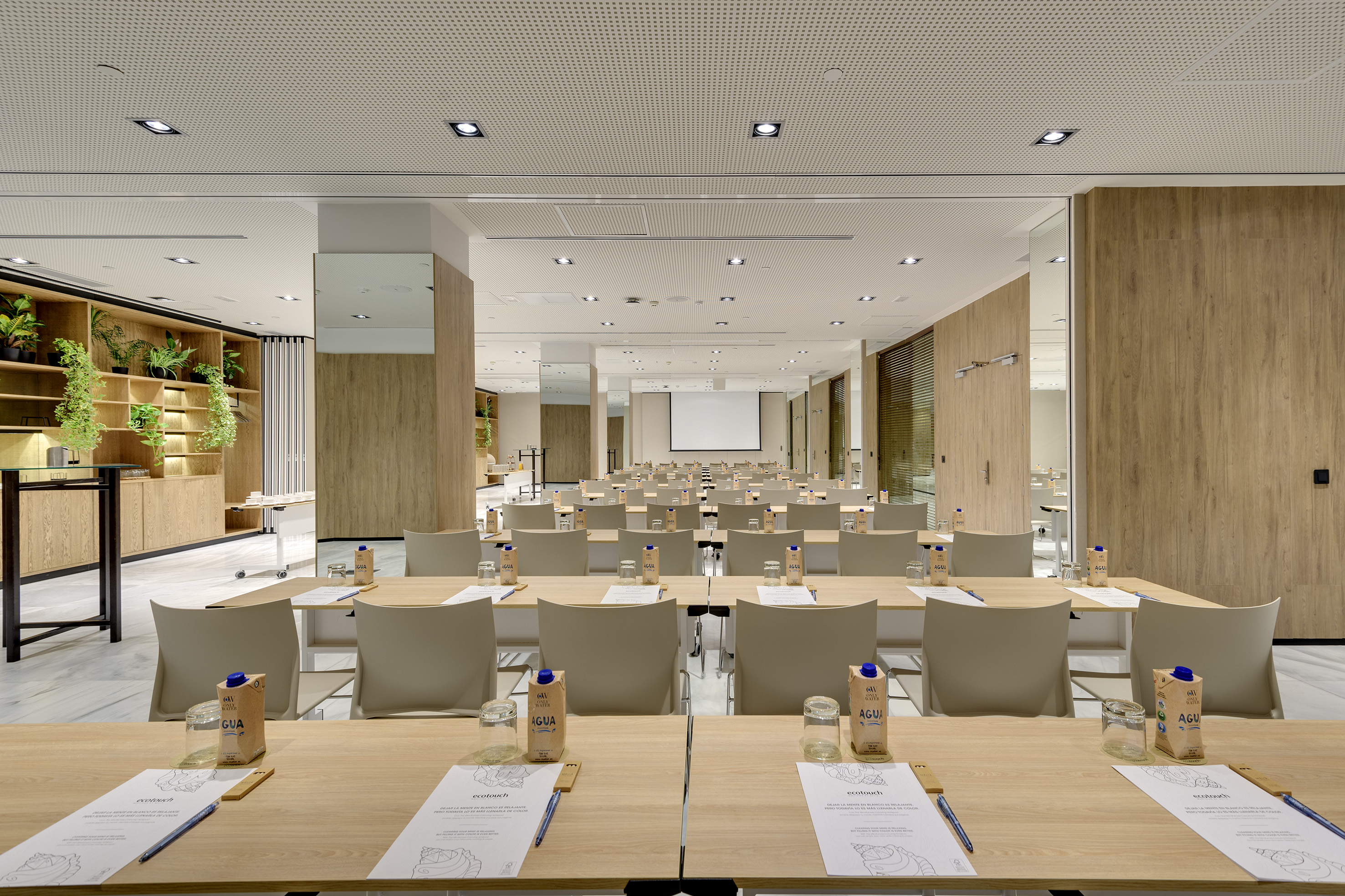 Modern conference room with tables, chairs, projection screen, and wood decor.