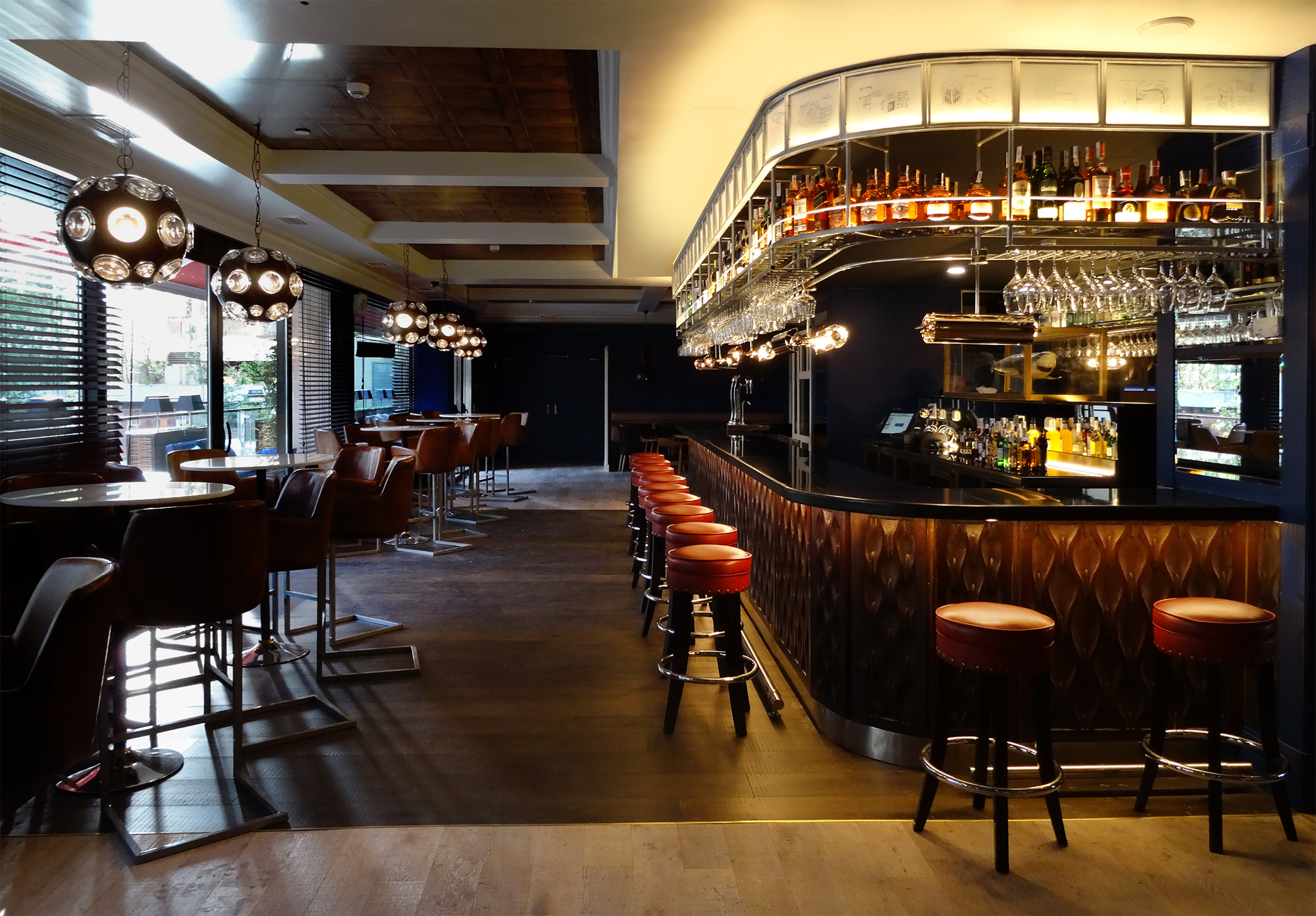 Modern bar interior with curved liquor display, red stools, and warm lighting.