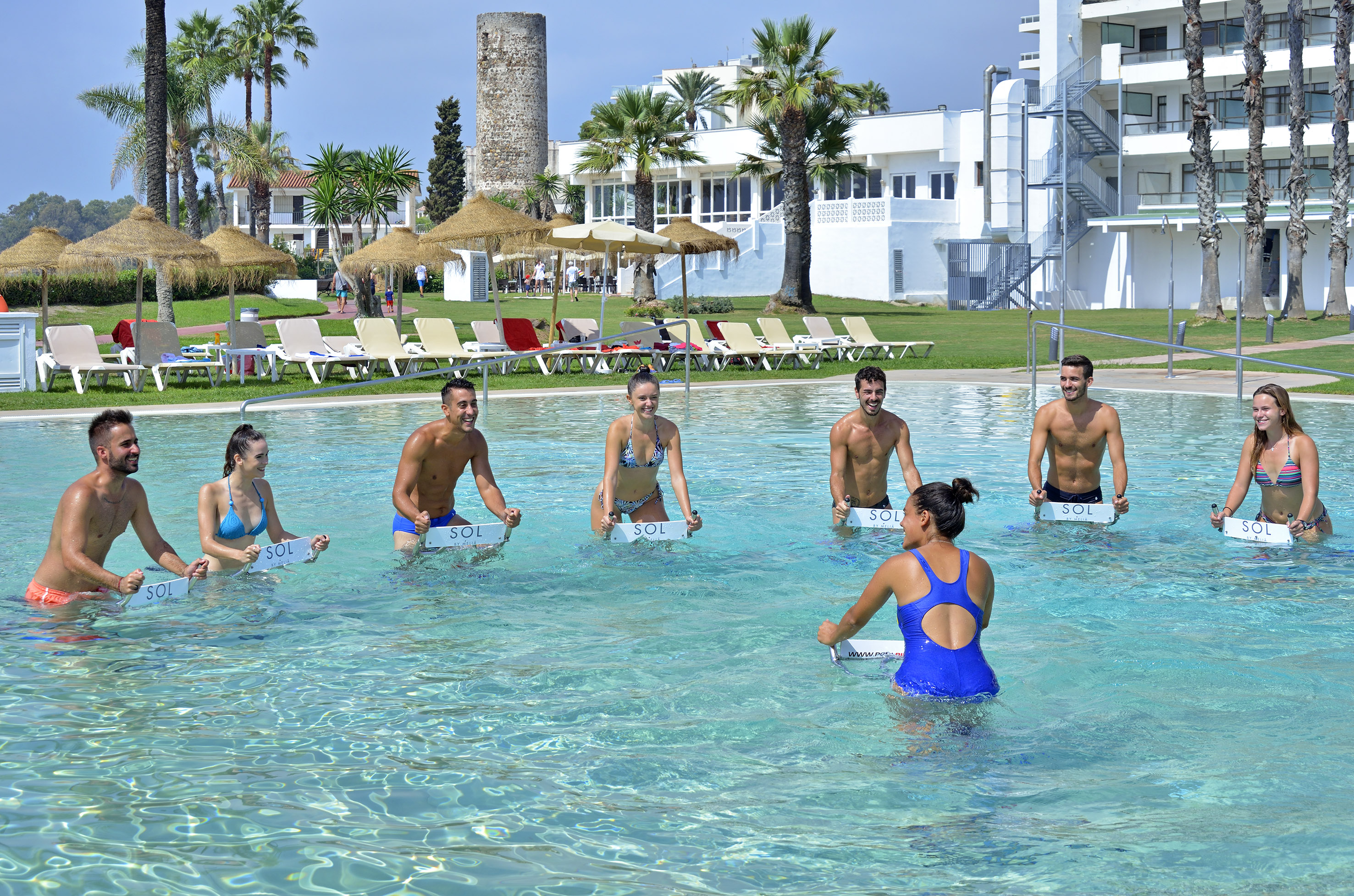 Guests doing SOL aqua cycling in a resort swimming pool with an instructor.