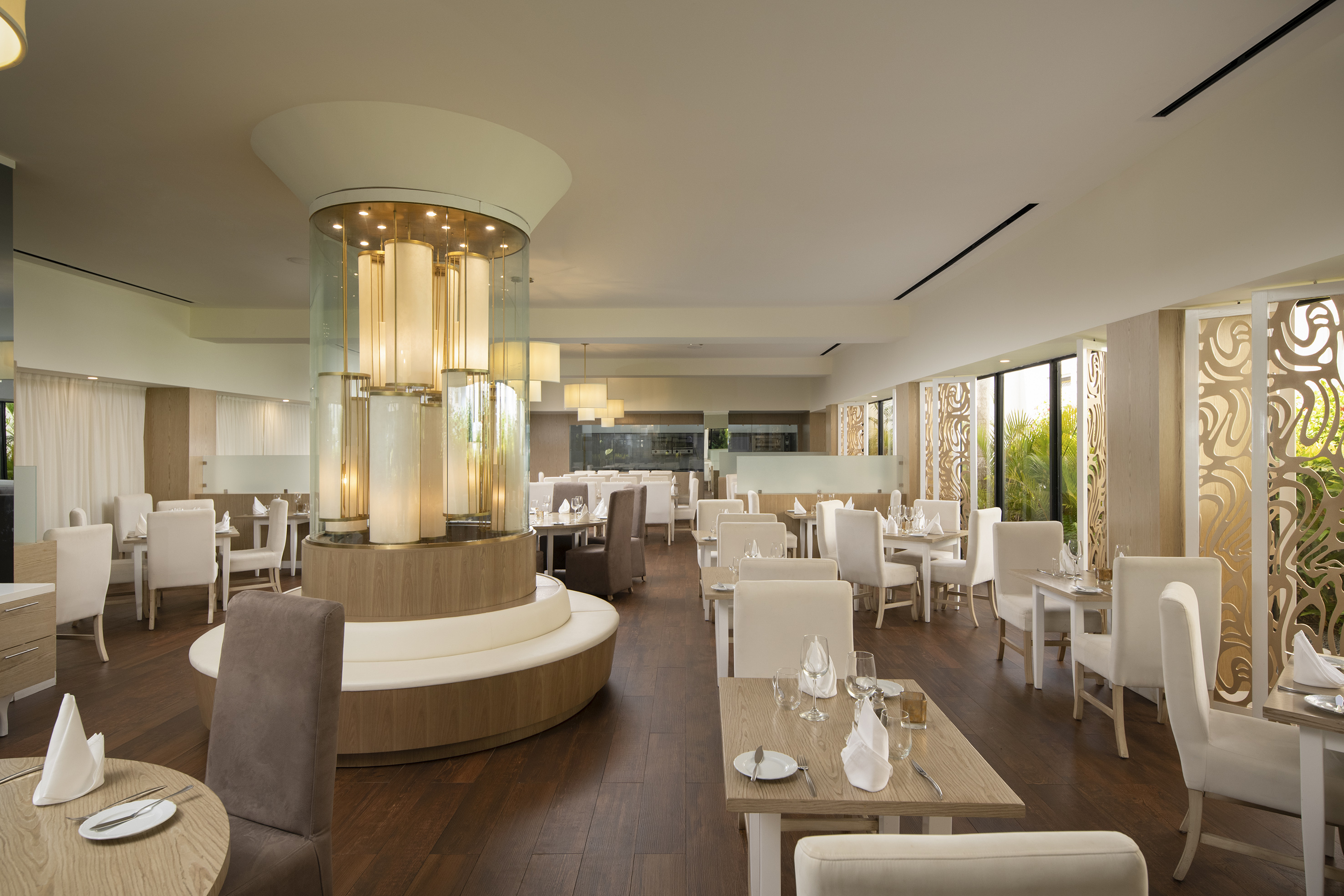 Bright, elegant restaurant with central illuminated pillar and set tables.