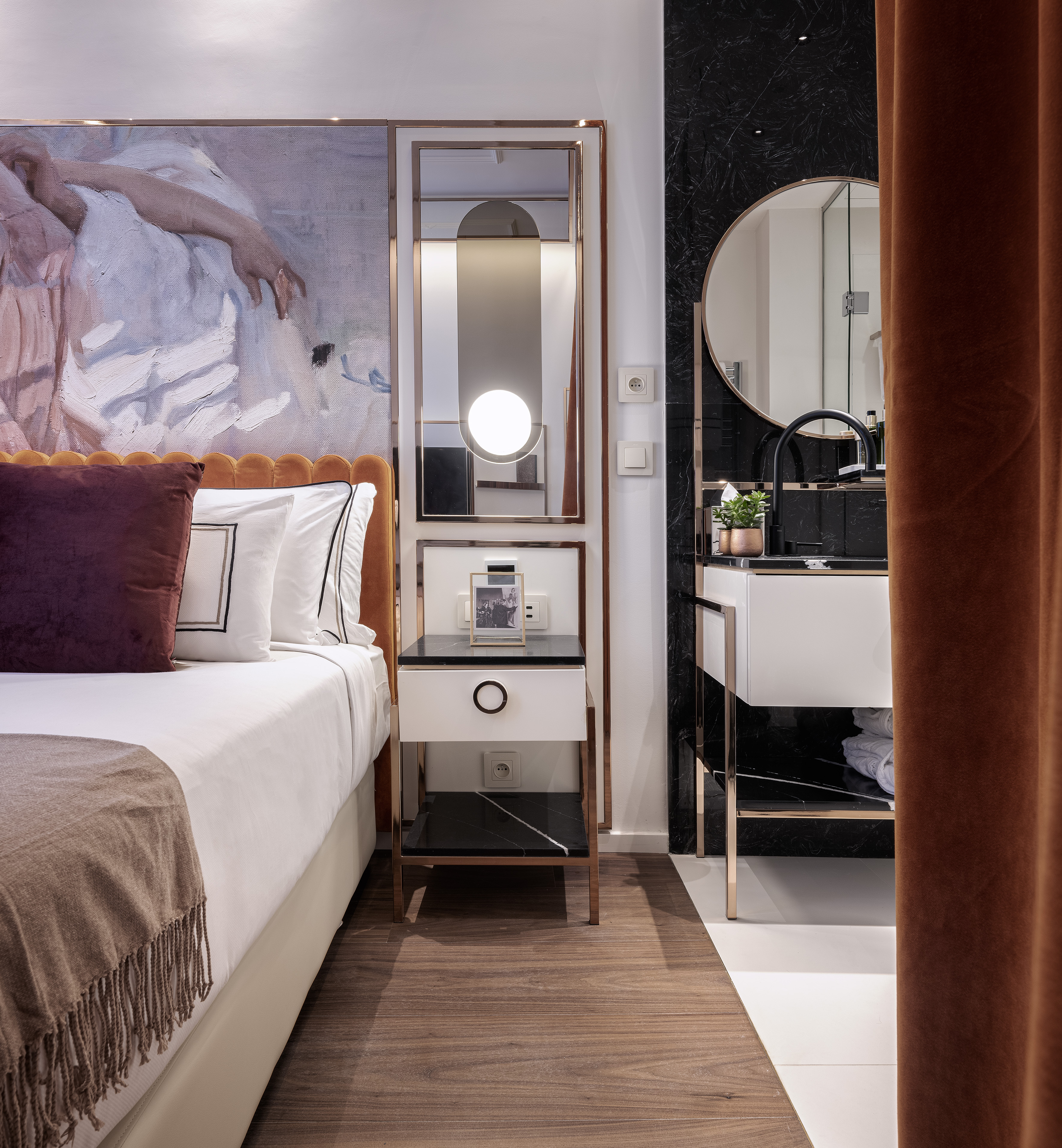 Luxury hotel room with bed, nightstand, vanity, black marble, and gold trim.