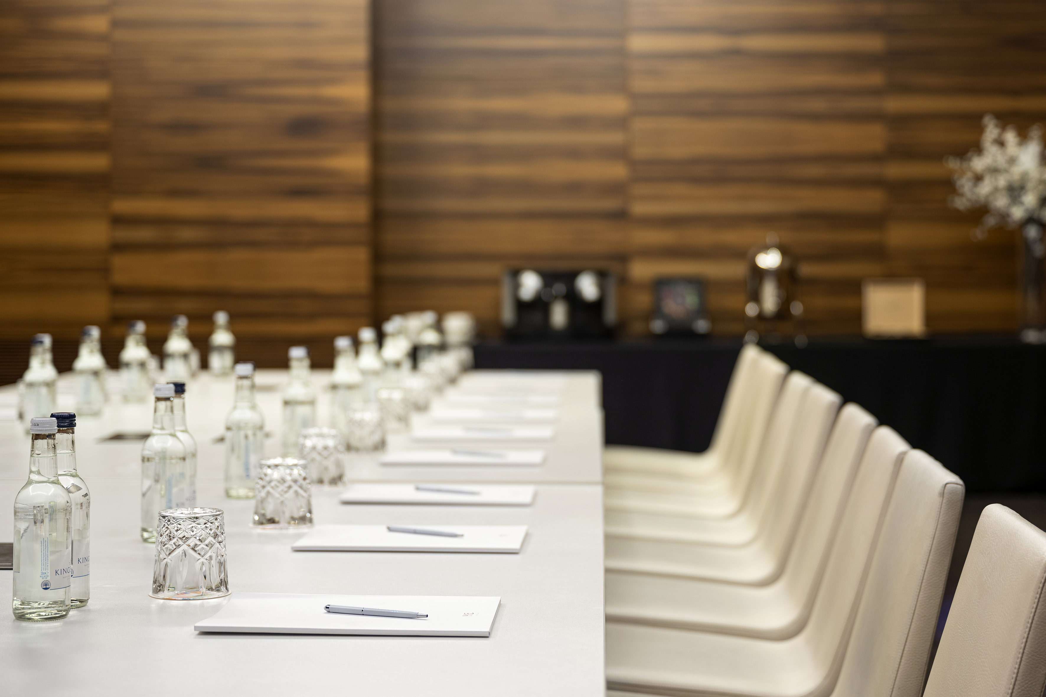Conference room table set with water bottles, notepads, pens, and chairs.