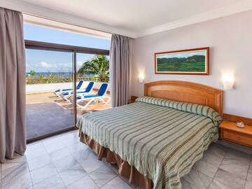 a bed with a glass door and a view of the ocean