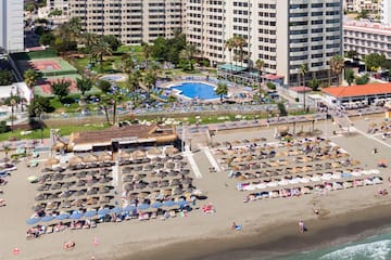 a beach with umbrellas and chairs and a swimming pool